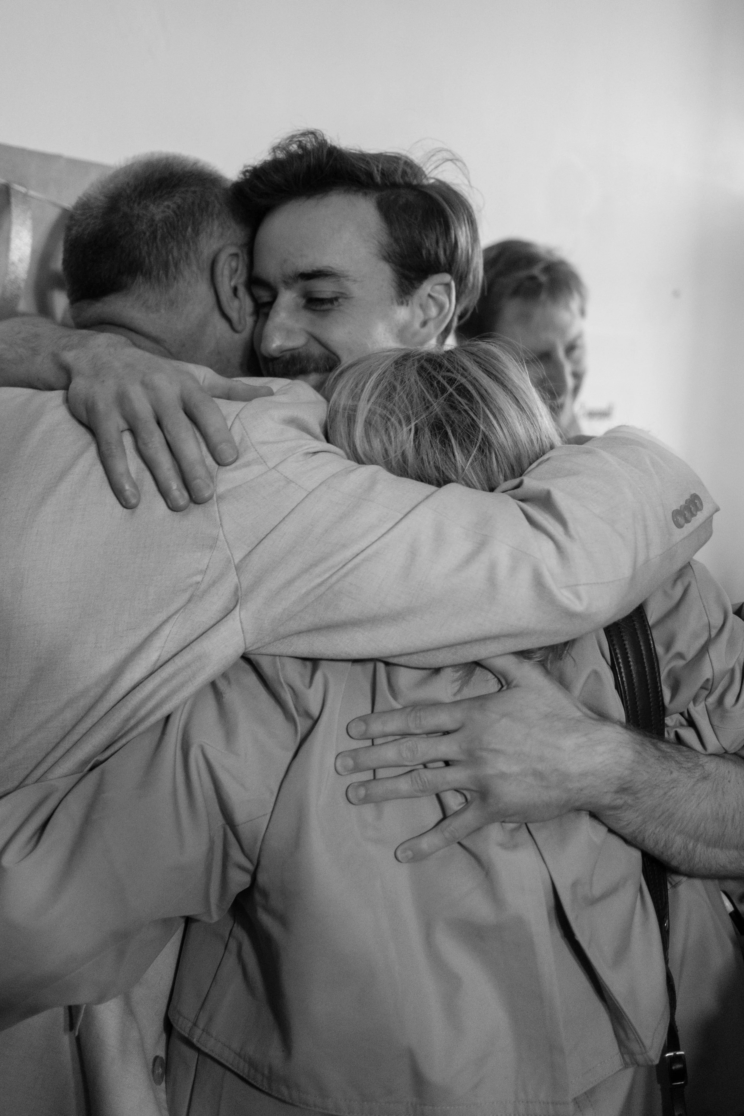 People hugging warmly in a group hug, smiling, in black and white.