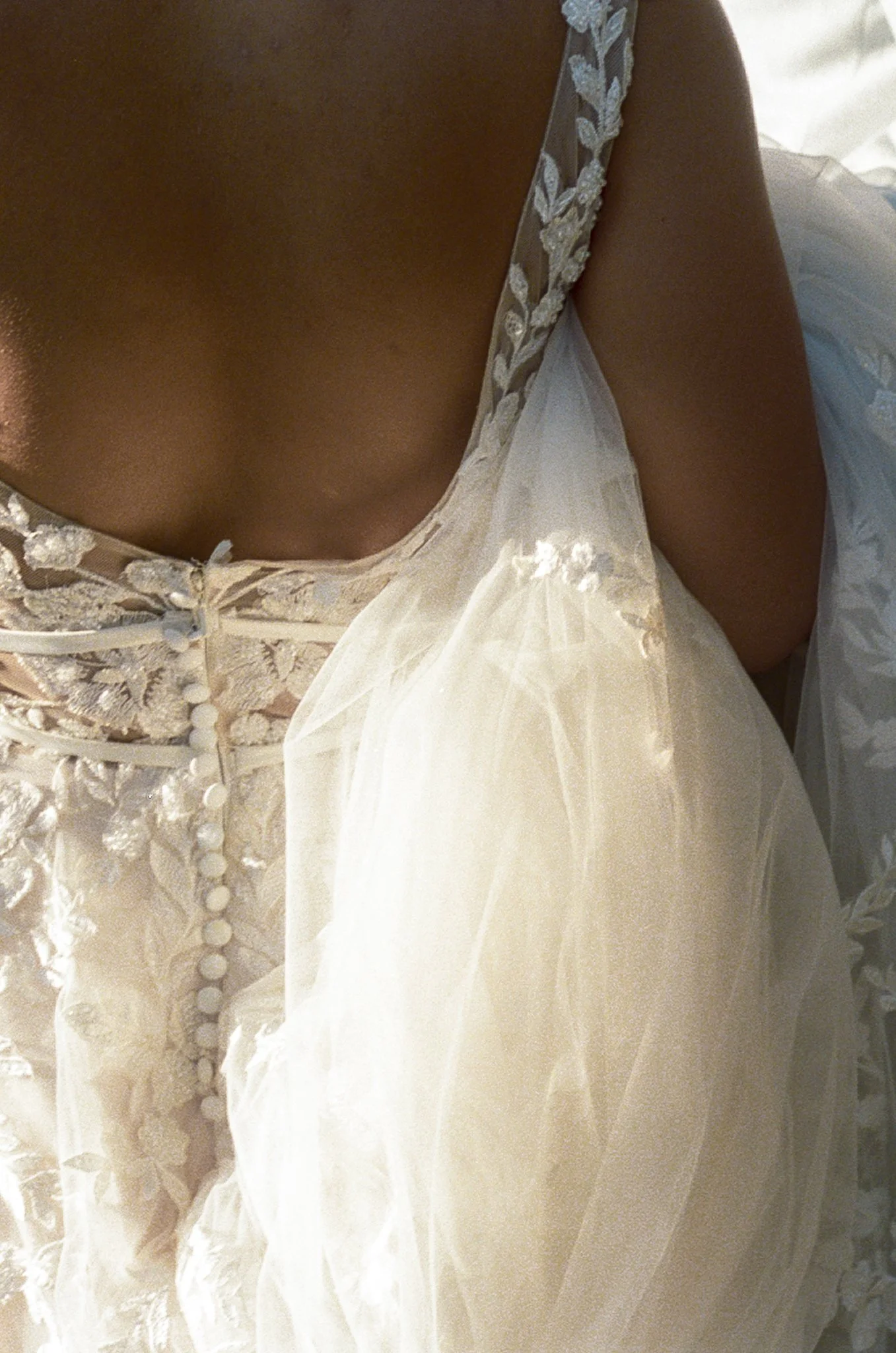 Close-up of the back of a woman wearing a white lace wedding dress.