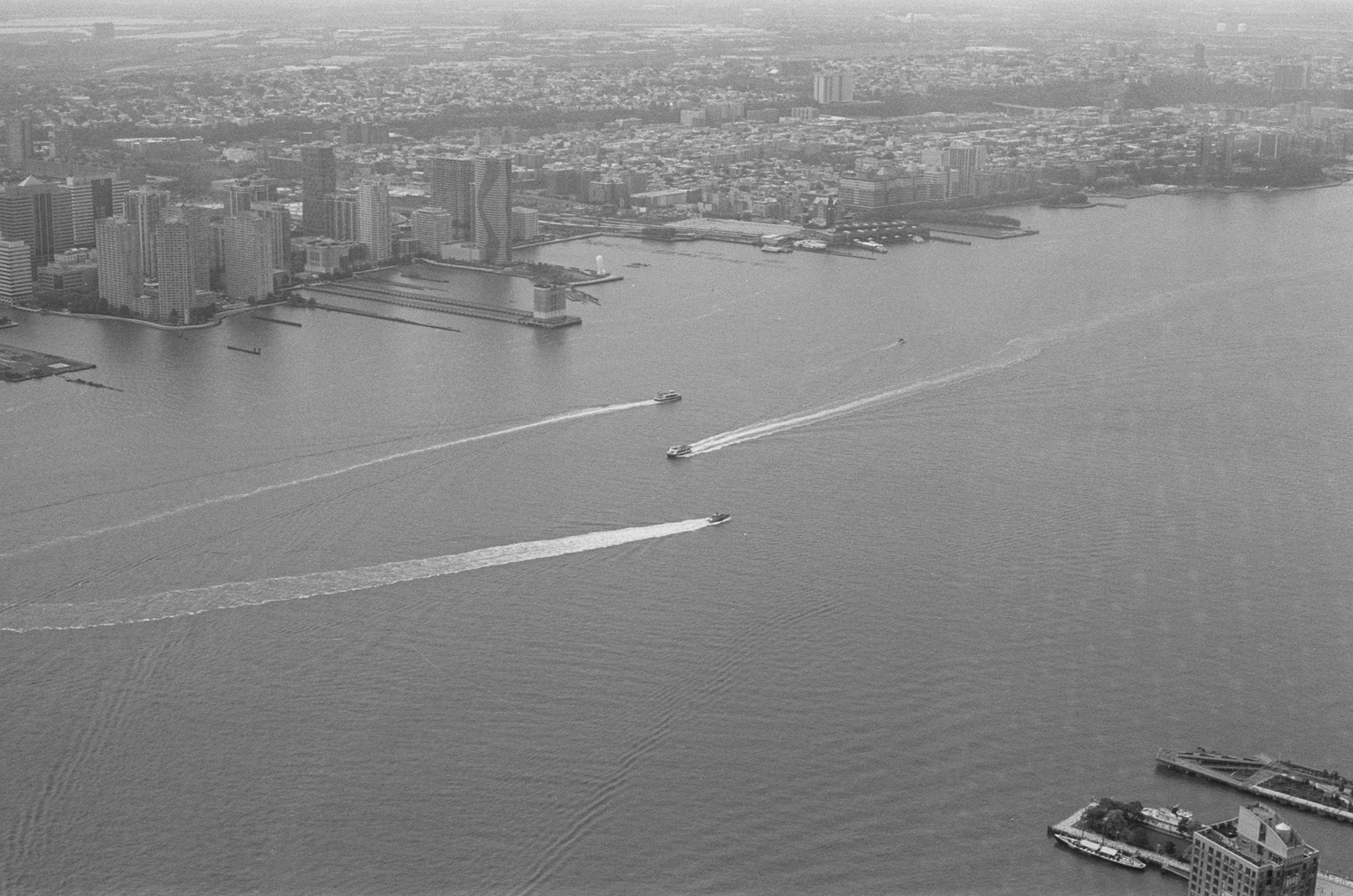 Aerial view of a city skyline with several boats moving across a large body of water.