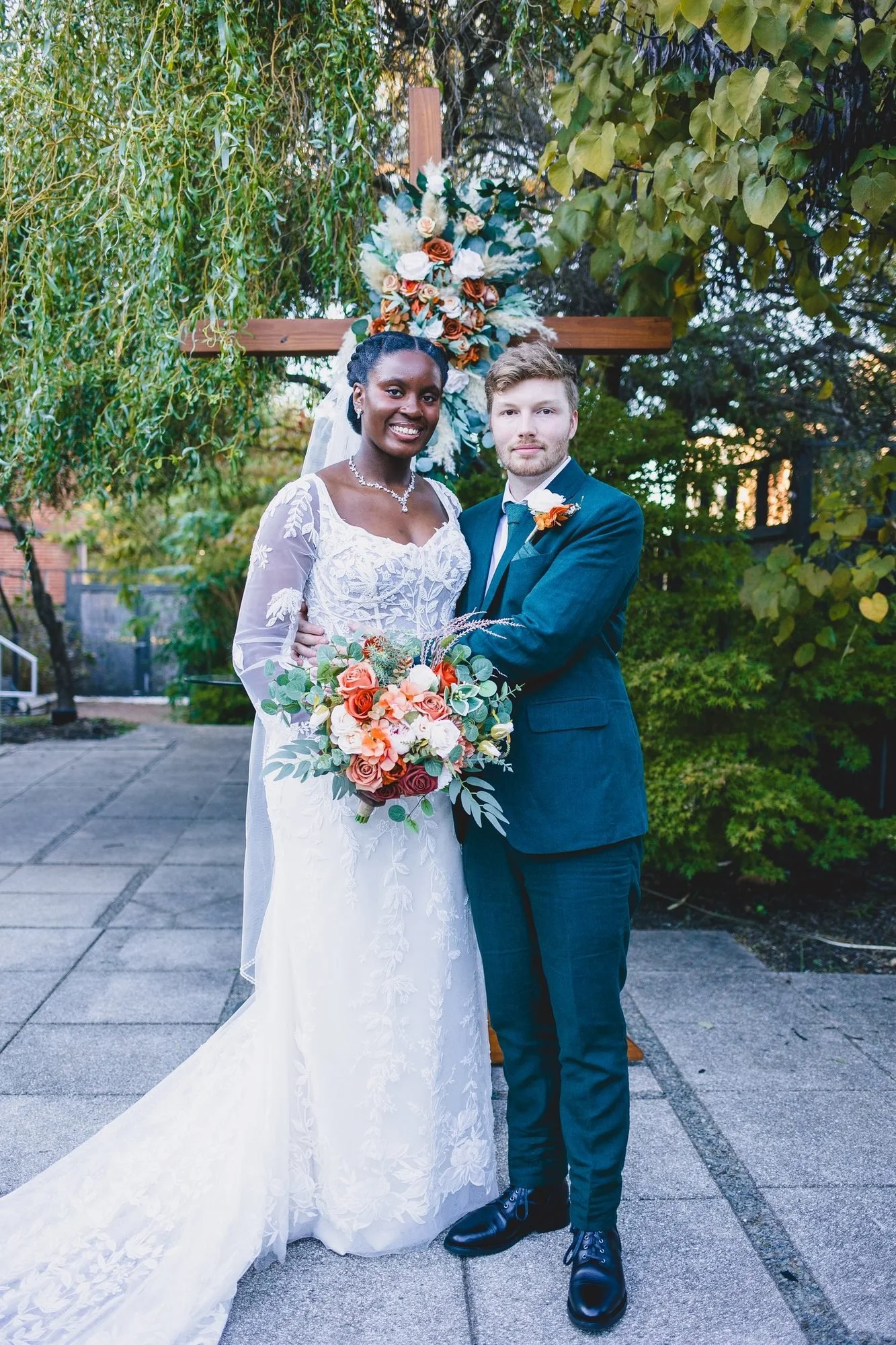 Couple under a floral ceremony arch at a fall wedding