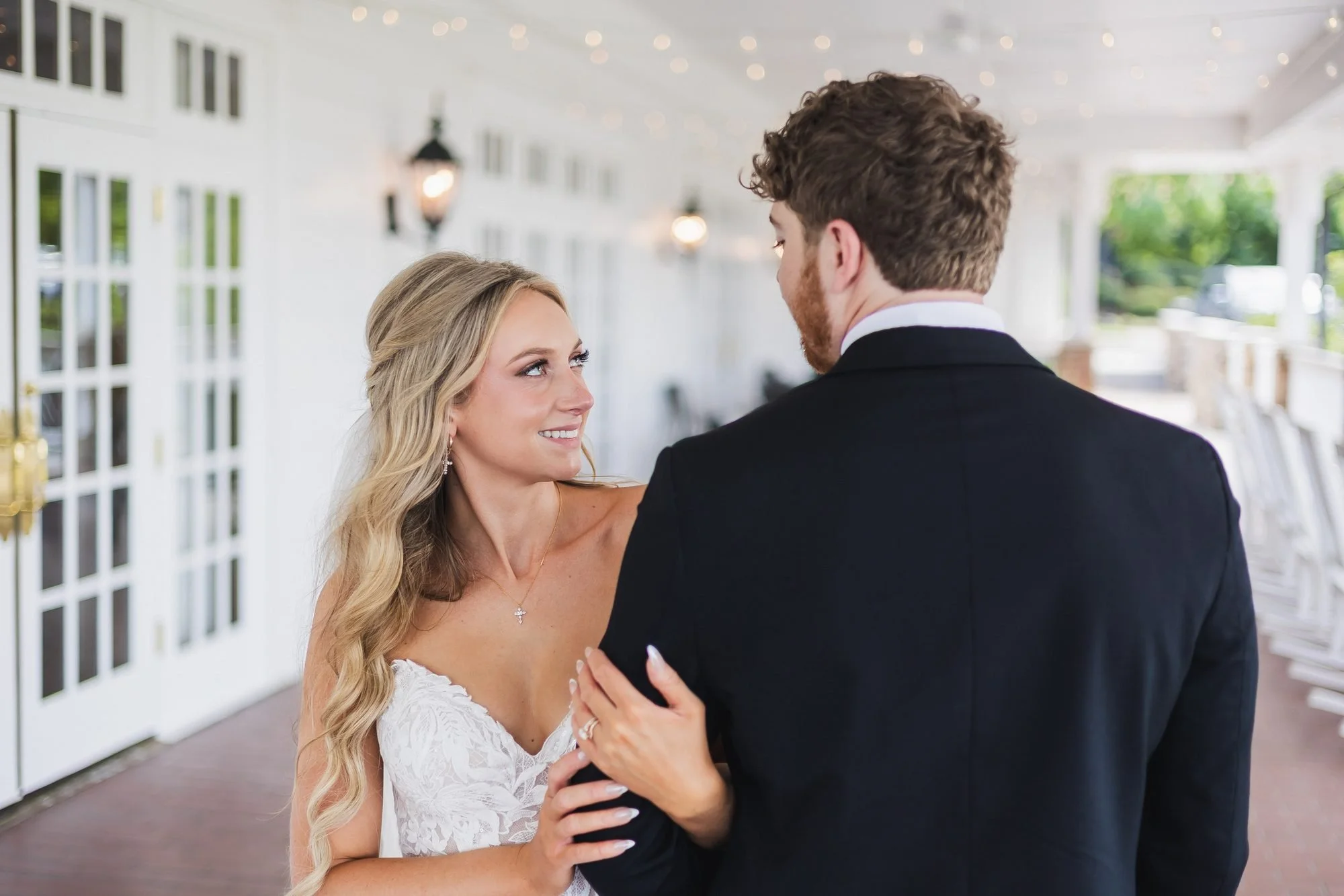 Alyssa and Colby wedding reception at Augusta Country Club in Augusta, Georgia: bride smiling over the groom's shoulder on the veranda.