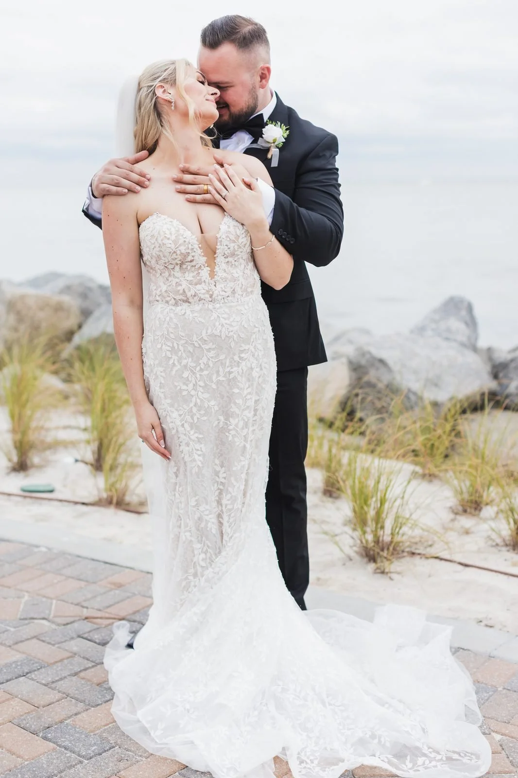 Groom embracing the bride from behind by the dunes at a Seabrook Island wedding near Charleston