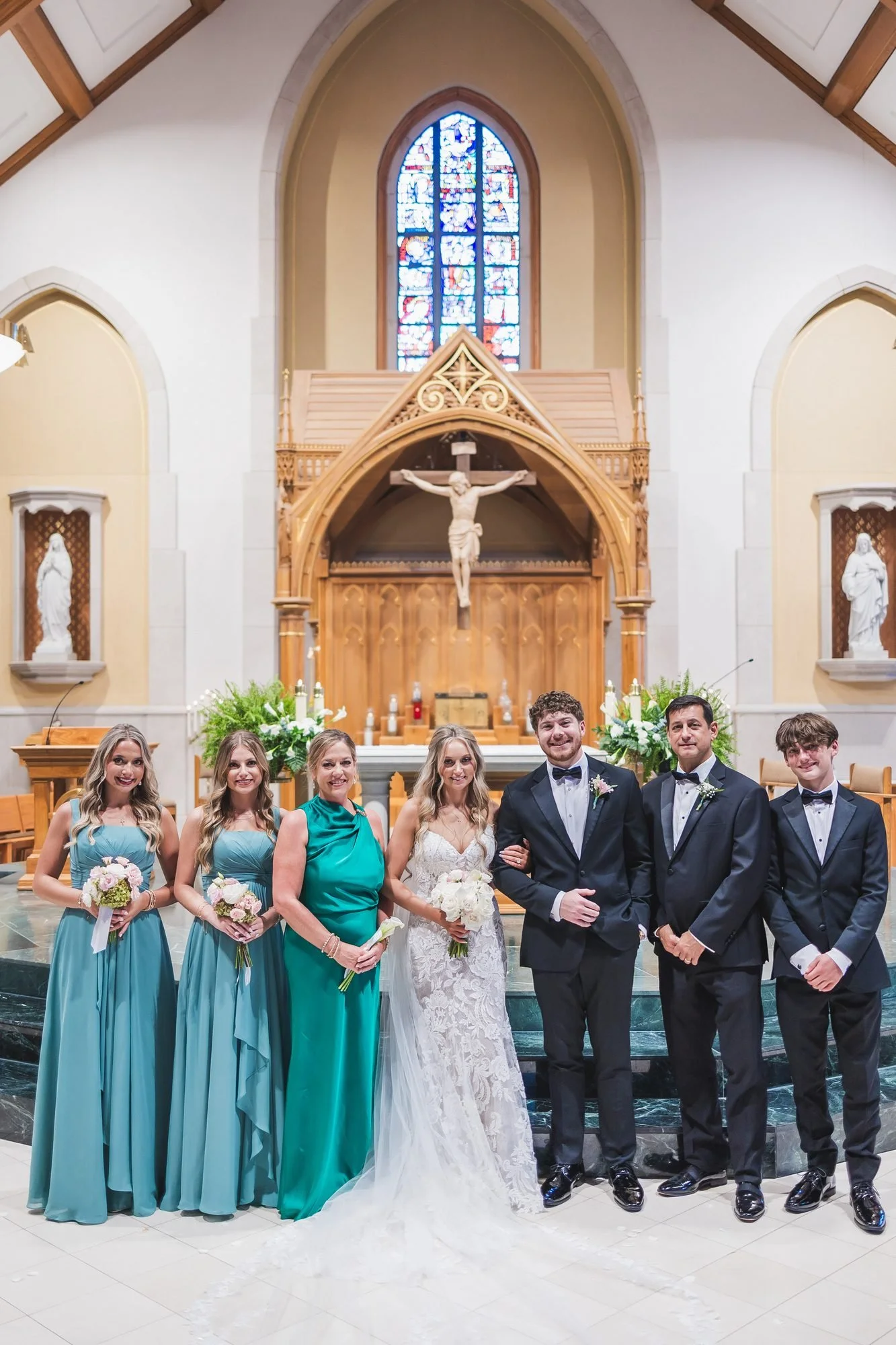 Alyssa and Colby wedding at St. Mary on the Hill Catholic Church in Augusta, Georgia: full wedding party at the altar under the stained-glass window.
