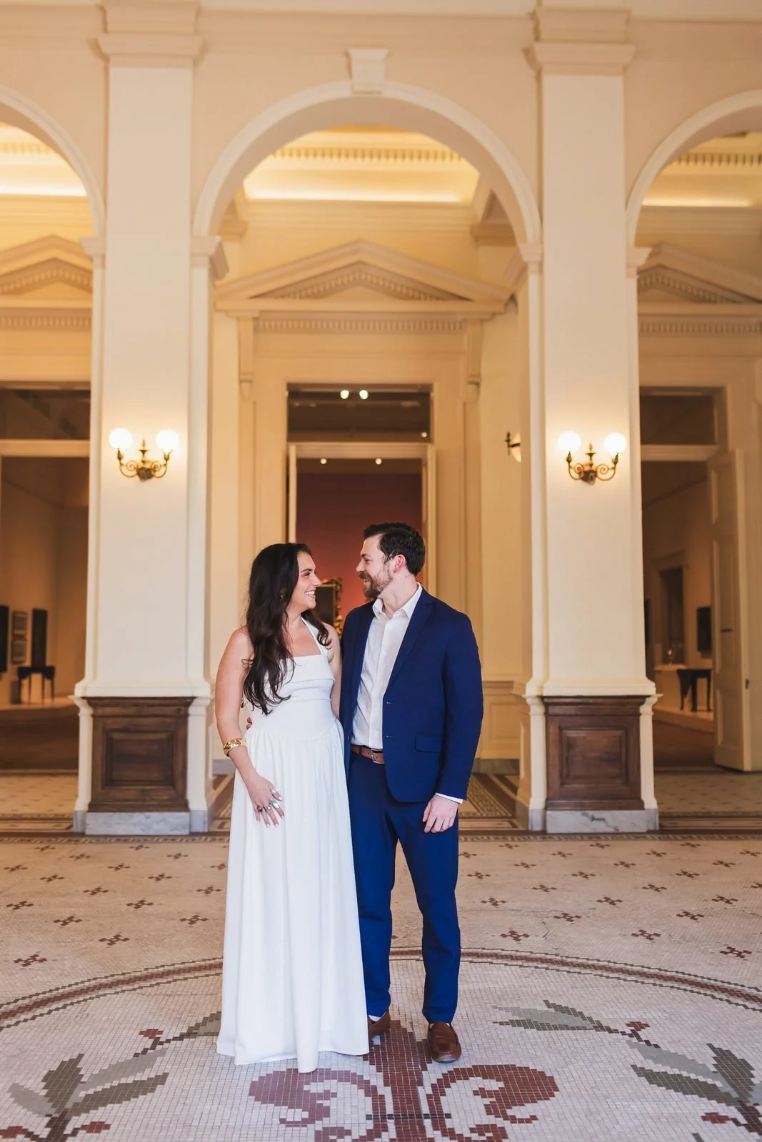 Engaged couple standing in the rotunda of the Gibbes Museum of Art in Charleston, with arches and a mosaic floor