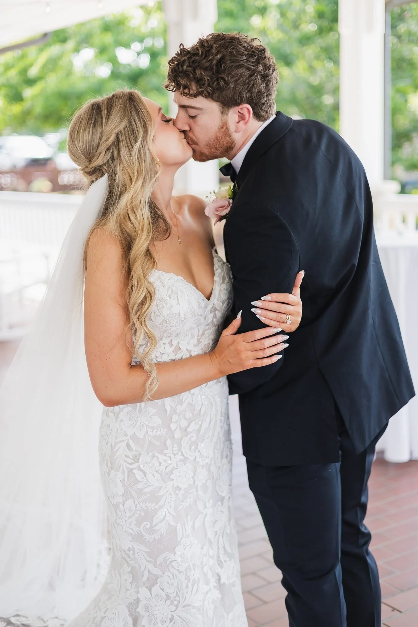 Alyssa and Colby wedding reception at Augusta Country Club in Augusta, Georgia: couple kissing on the white-columned veranda.