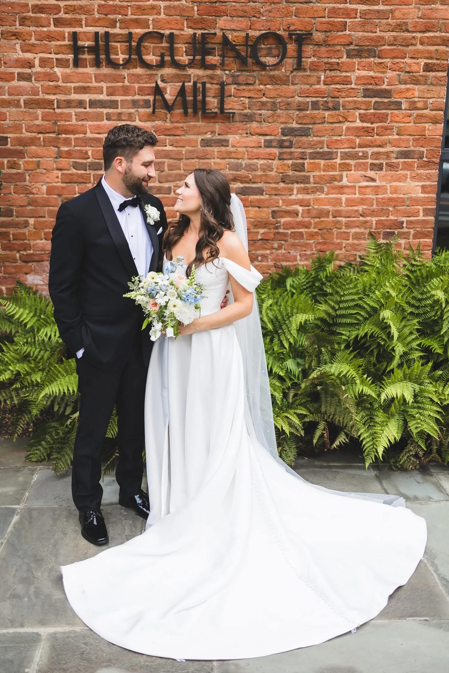 Madison and Derek's wedding portrait in front of the Huguenot Mill sign in downtown Greenville, South Carolina.