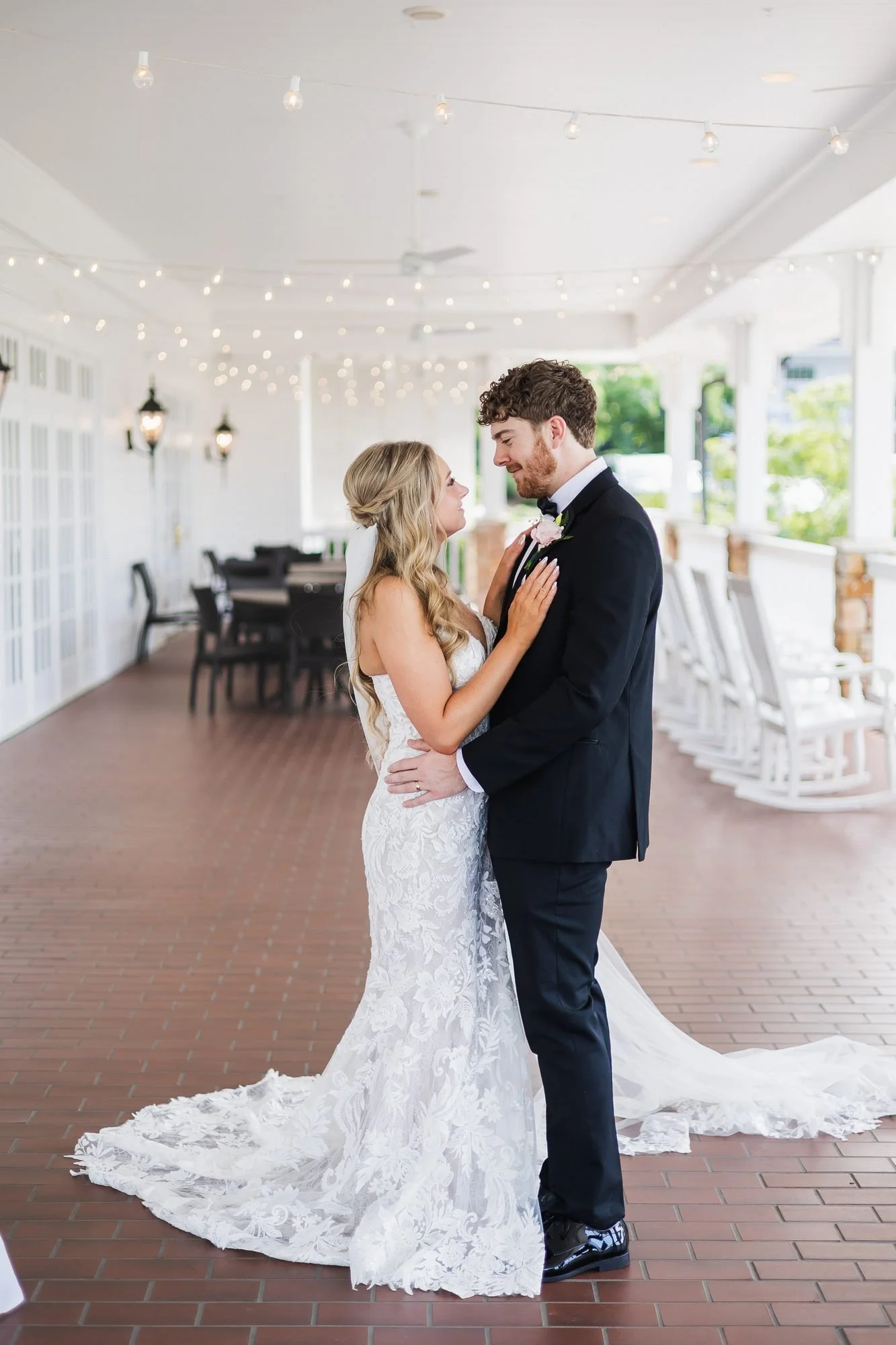 Alyssa and Colby wedding reception at Augusta Country Club in Augusta, Georgia: full-length couple portrait on the veranda with the bride's long train.