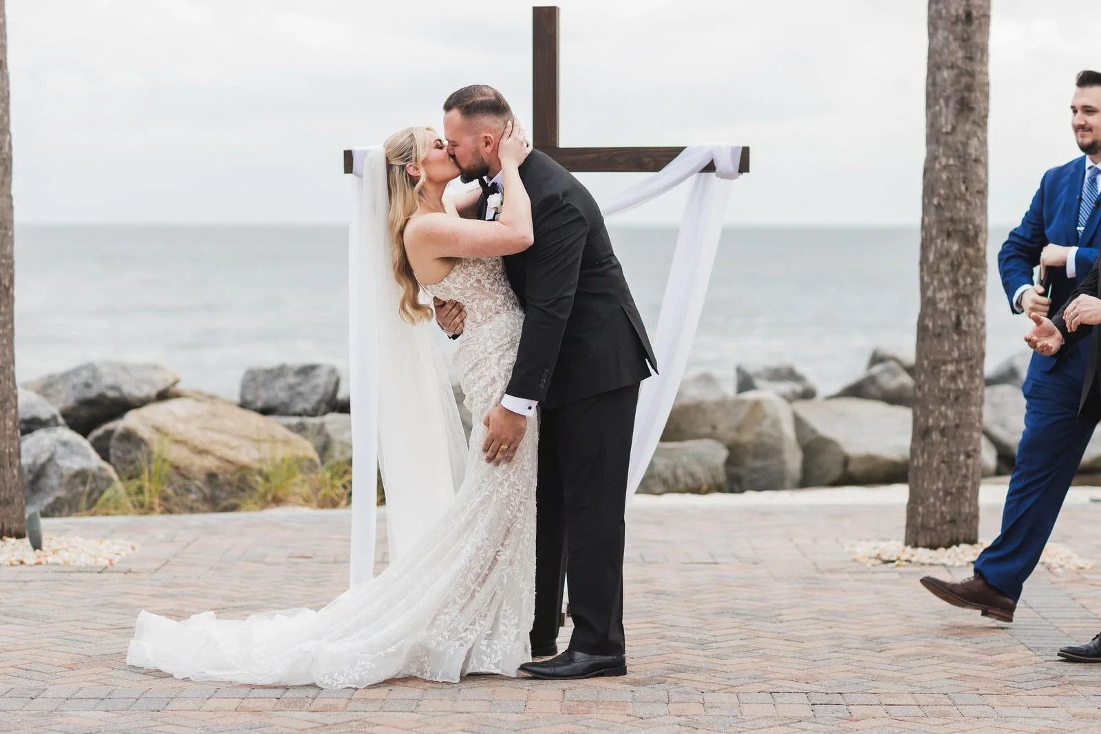 First kiss at a wooden cross arbor with the ocean behind them on Seabrook Island near Charleston