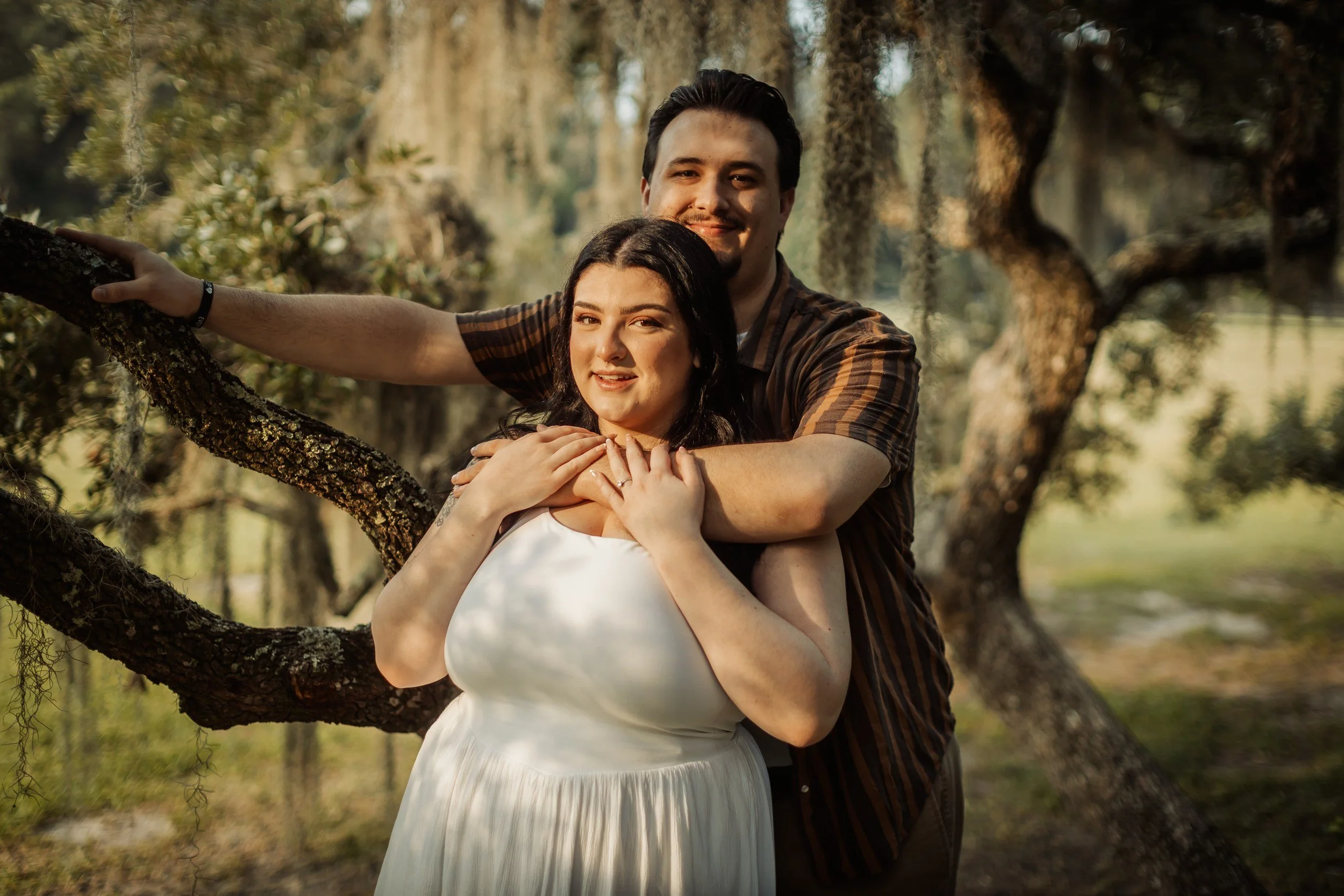 Smiling engaged couple embracing under Spanish moss at Magnolia Plantation, Charleston