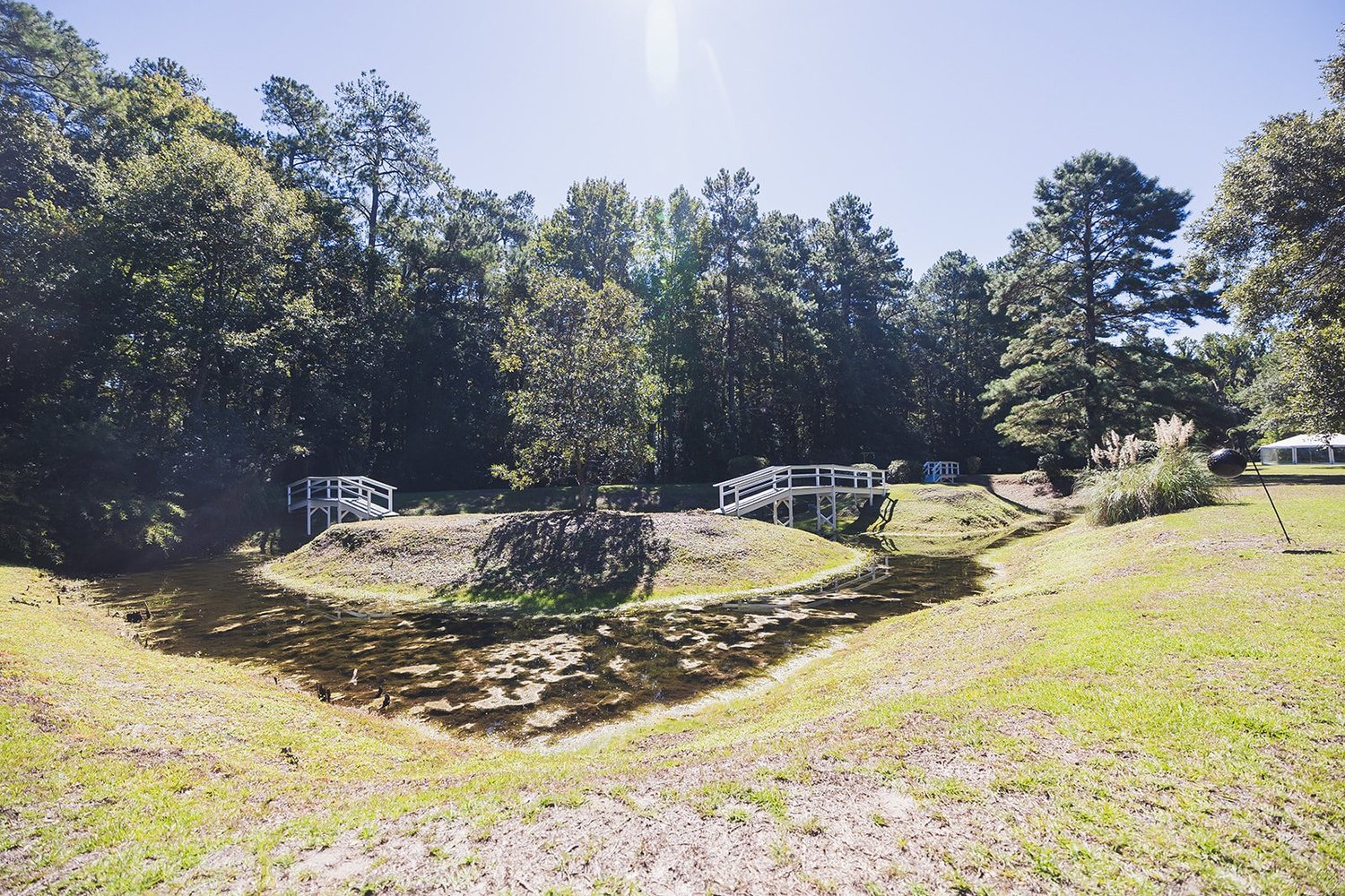 Two white footbridges on the grounds at Wicklow Hall in Georgetown, South Carolina, surrounded by tall pines and live oaks.