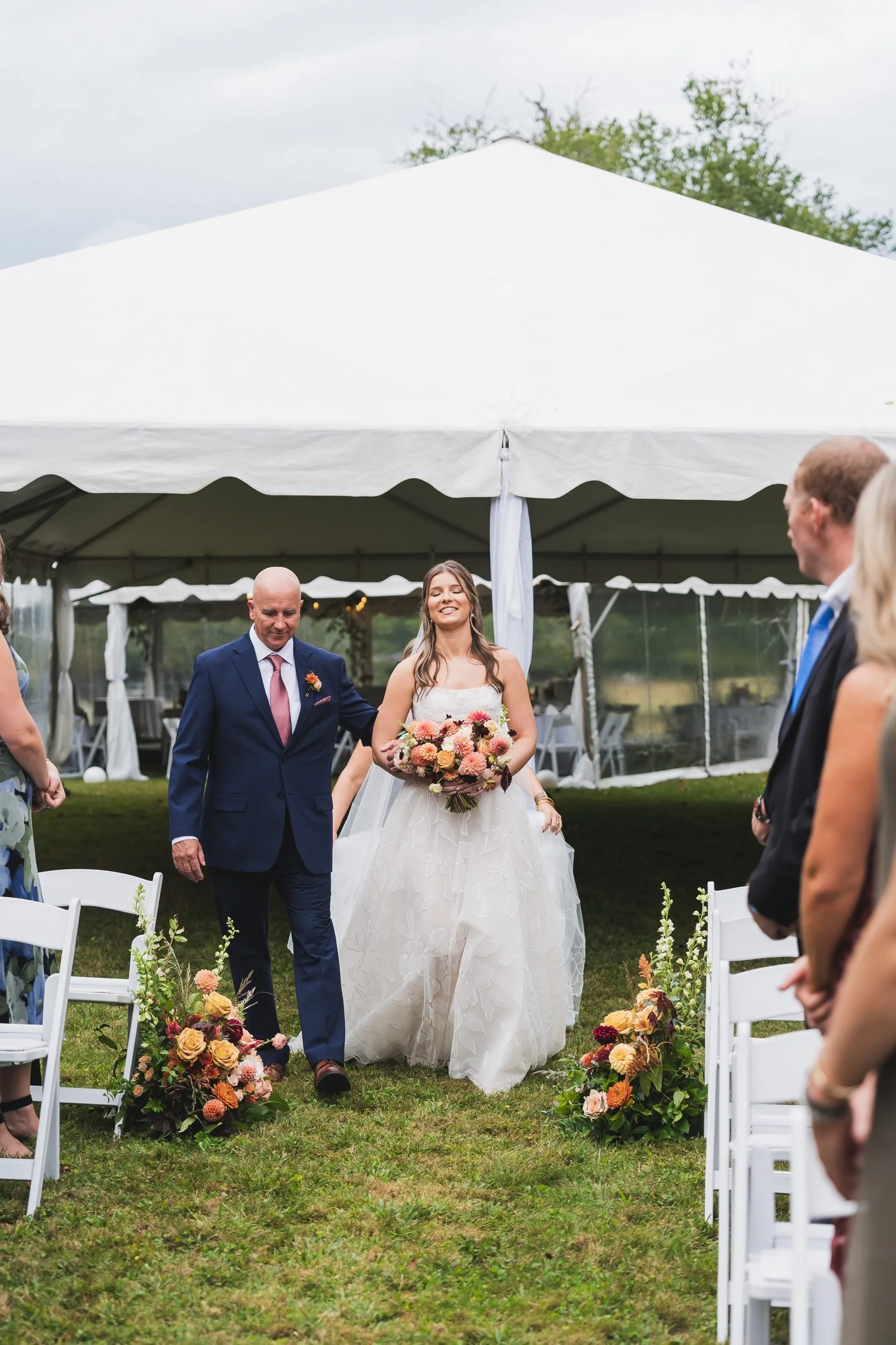 Aisling and Neal's wedding in Flat Rock, North Carolina. The bride walks down the aisle with her father under a white tent.