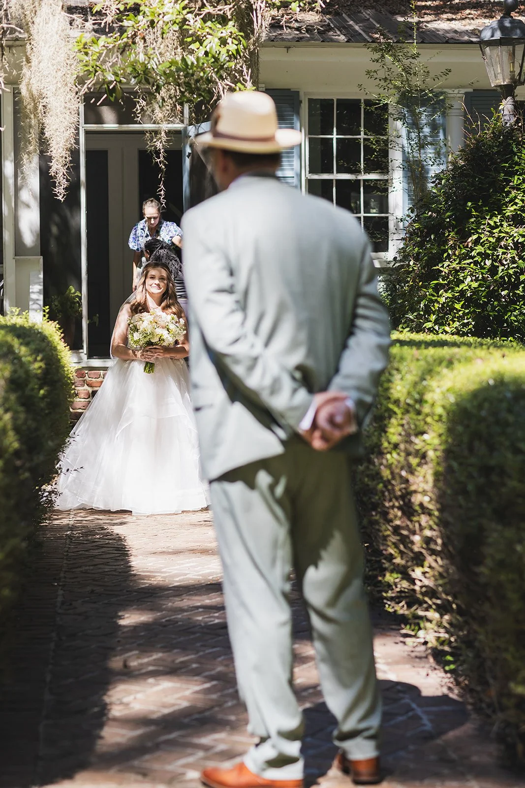 Sarah smiles as she steps out onto a brick garden path lined with clipped hedges and Spanish moss at Wicklow Hall in Georgetown, South Carolina.