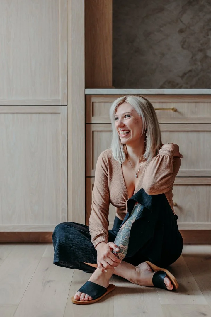 Korinna sitting on the kitchen floor in front of custom cabinetry during a home organizing project, part of professional organizing services in New Hampshire that support decluttering services for real homes.