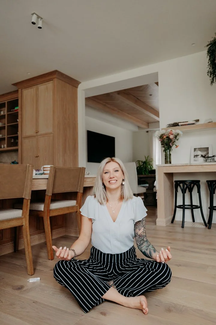 Korinna, home design feng shui seated on the floor in a calm, open home environment, demonstrating grounding practices that support balanced energy and flow.