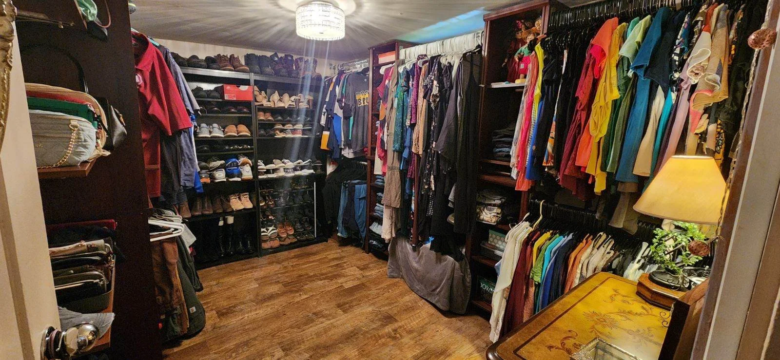 A walk-in closet filled with colorful clothing, shoes, and accessories on shelves and hanging racks.