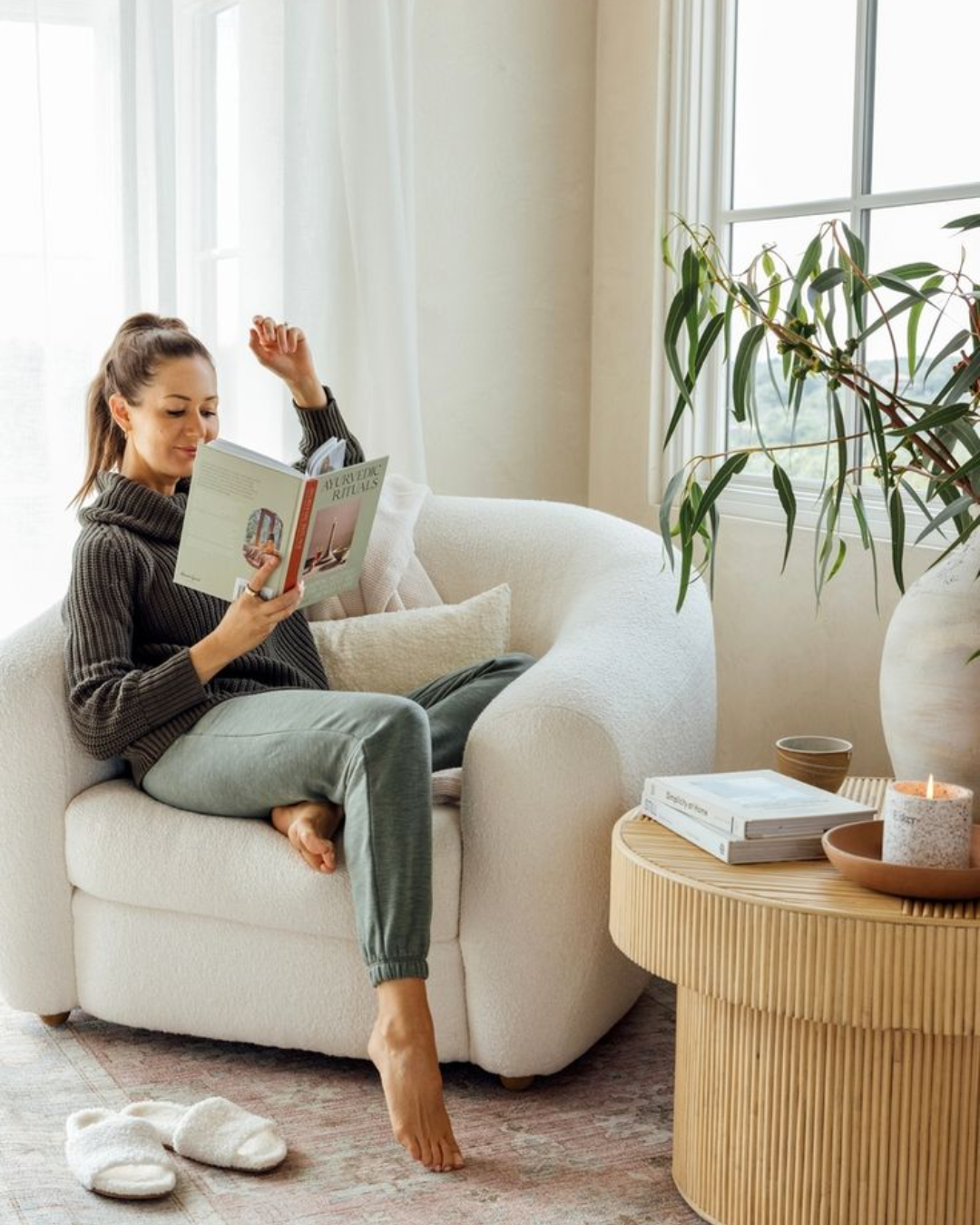 Woman reading in living room with neutral sofa, throw pillows, and natural light after decluttering services, showing a simplified space with minimal furniture and clear surfaces.
