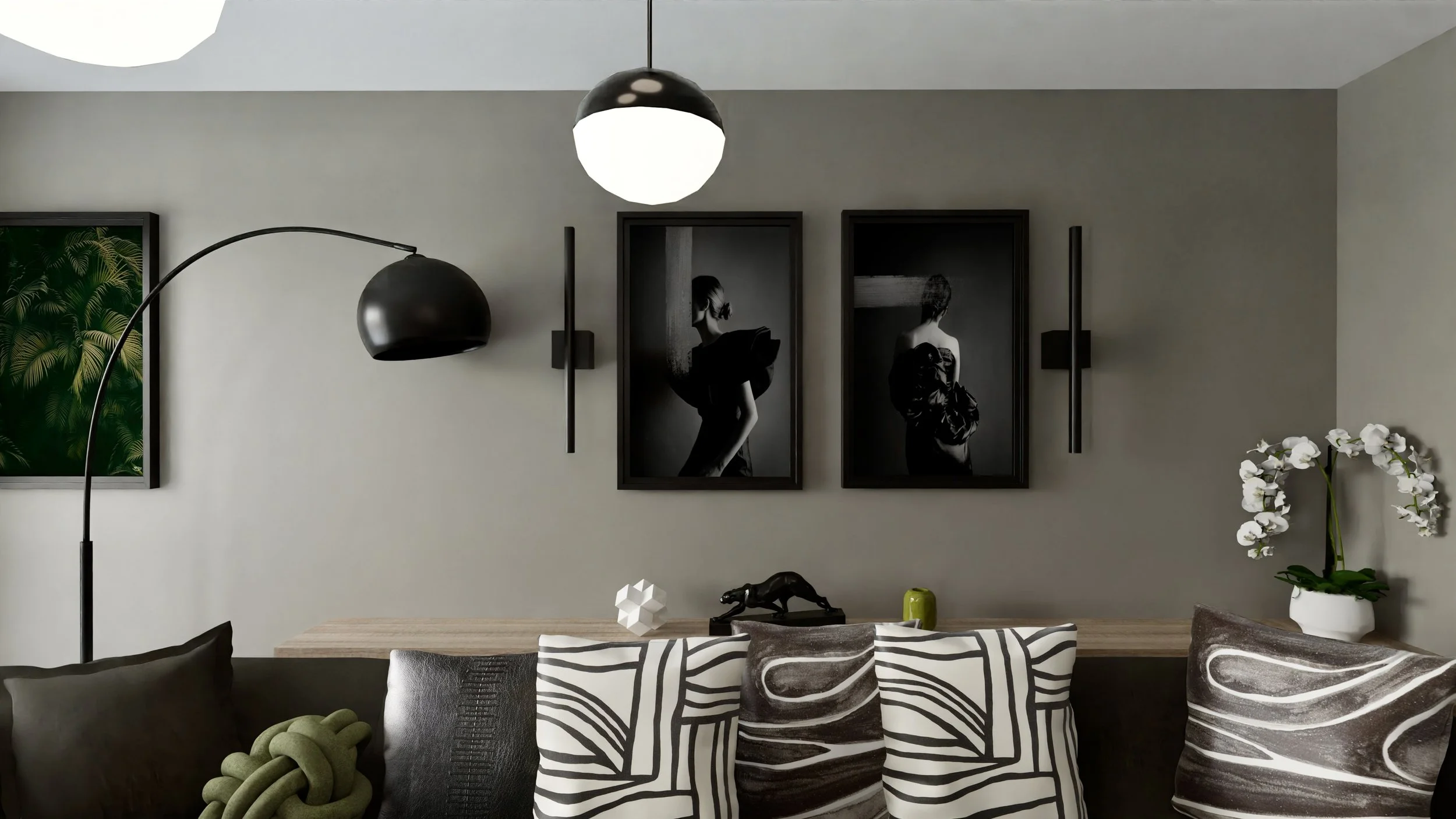 Modern living room with a gray wall, black and white framed photographs, black wall sconces, a black floor lamp, a wooden sideboard, white decorative objects, a black dog sculpture, a potted orchid, and patterned pillows on a sofa.