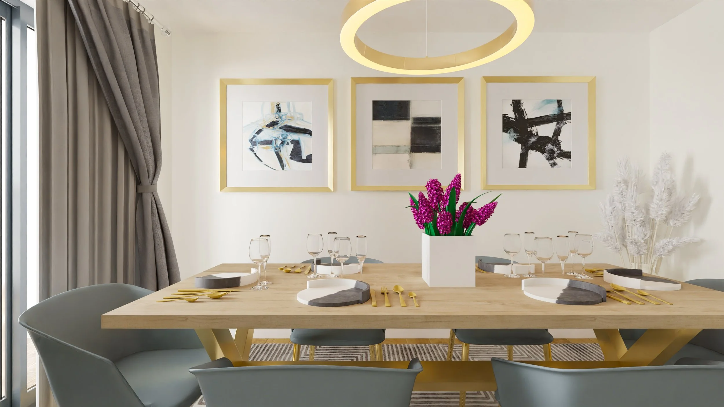 Modern dining room with a light wood table, gray chairs, and gold accents. The table is set with gold utensils, wine glasses, and decorative black and white trays. A large white planter with purple flowers sits in the center, with a white vase of white dried pampas grass in the background. Artwork hangs on the wall, and a contemporary circular ceiling light illuminates the room.