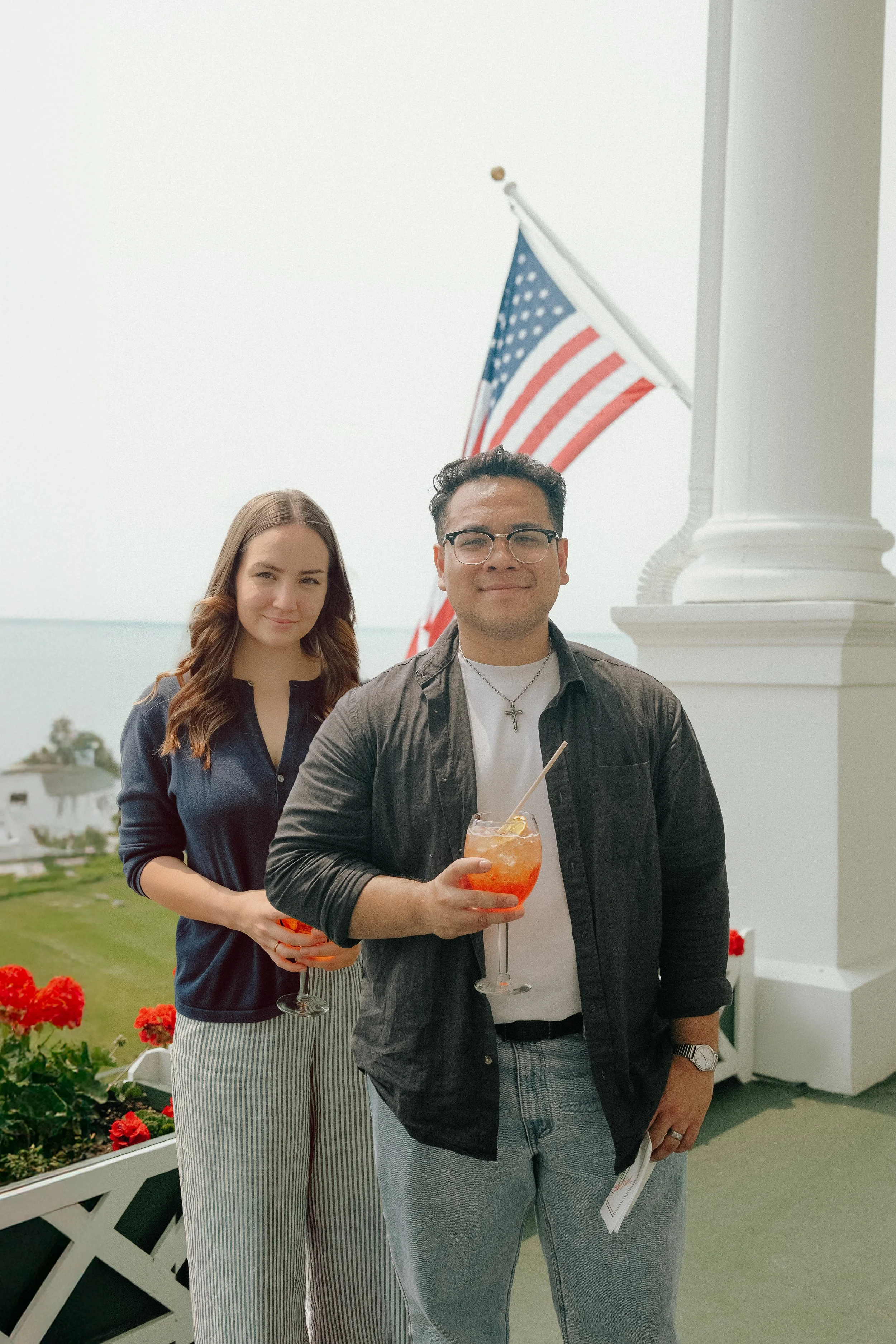 owners michael and sarah holding aperol spritzes on the patio at Mackinac Island