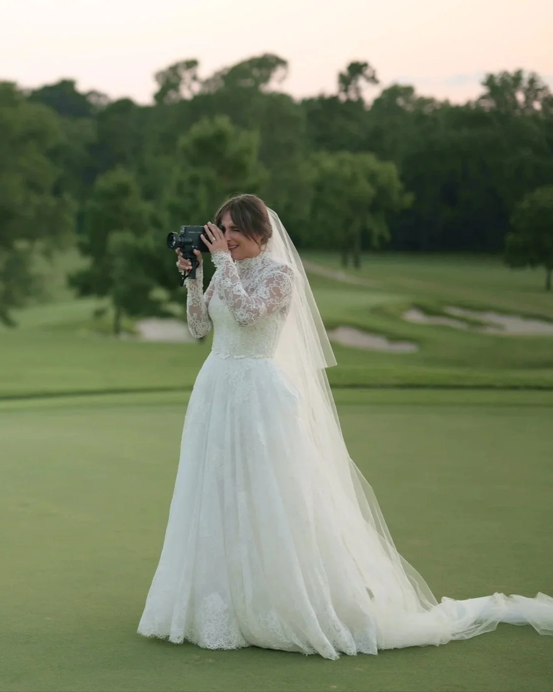 Bride in a lace wedding dress holding a Super 8 camera