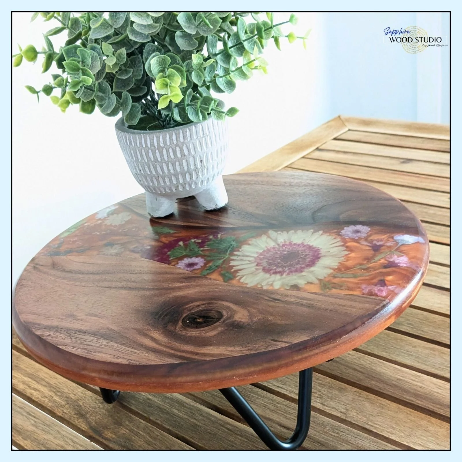 Chelsea made this beautiful plant stand during a recent epoxy resin class. I love how the wood grain and knot pop once finished. 
Her orange swirl adds some intrigue to these perfectly placed petals. We added the legs and customized with a laser engr