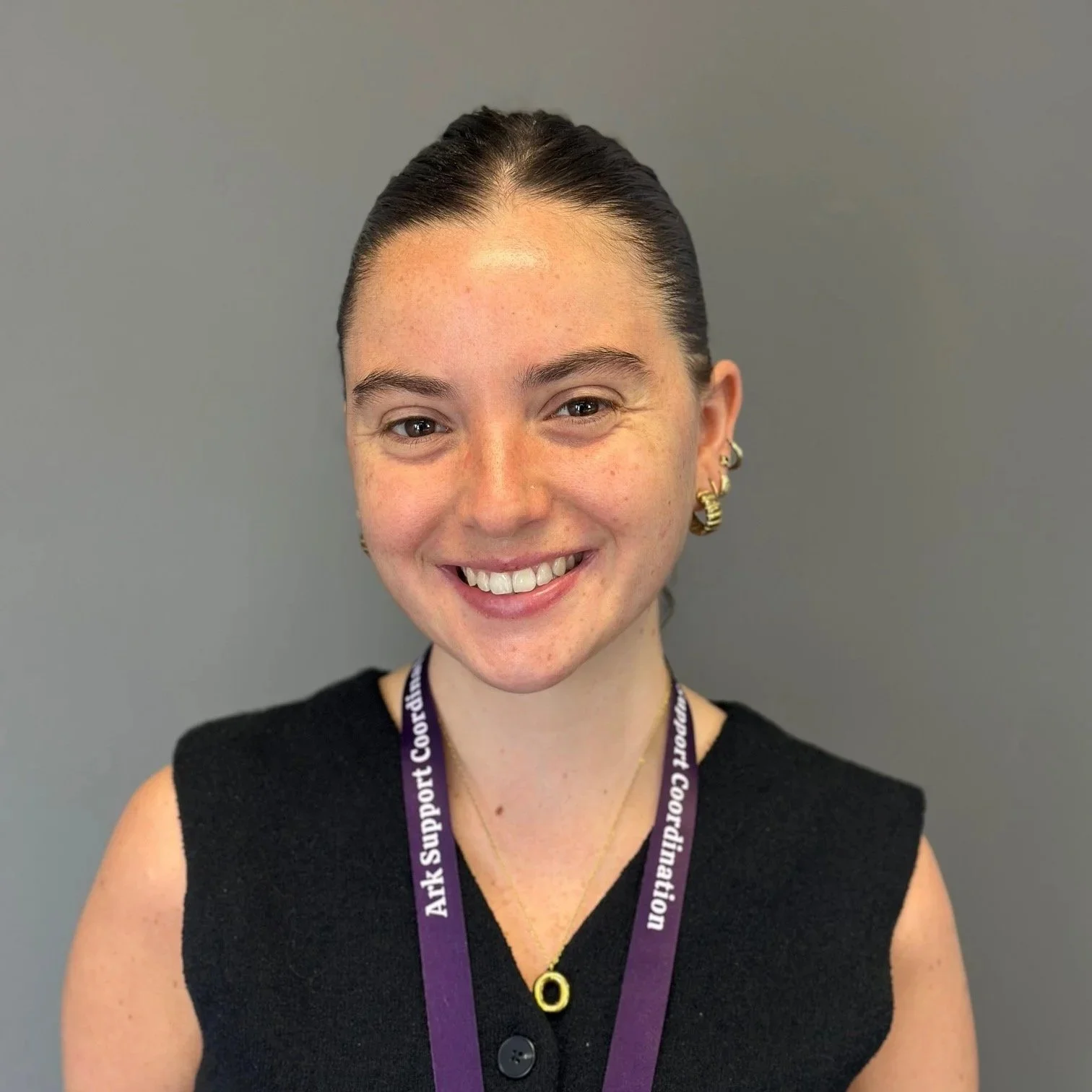 A headshot of Elena. Elena has long curly hair and is in a floral shirt.