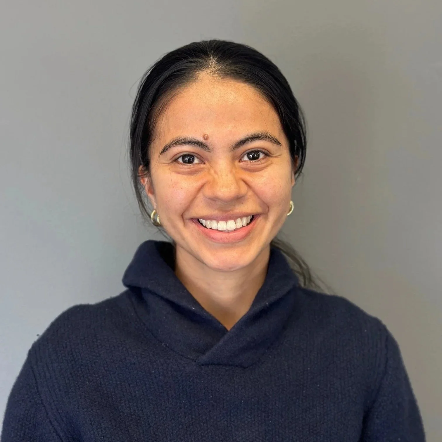 A headshot of Thalia smiling. Thalia has long blonde hair and is in a white top.