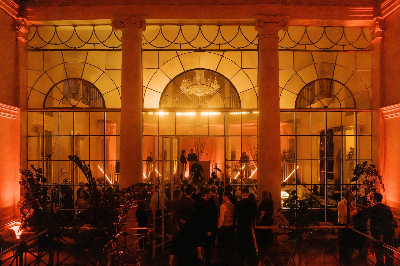 A stage set for a performance with a large screen displaying a moonlit forest scene. The audience is sitting on the floor on cushions, watching the performance. The stage is decorated with yellow and green leaf-patterned curtains and lit with colorful stage lights.