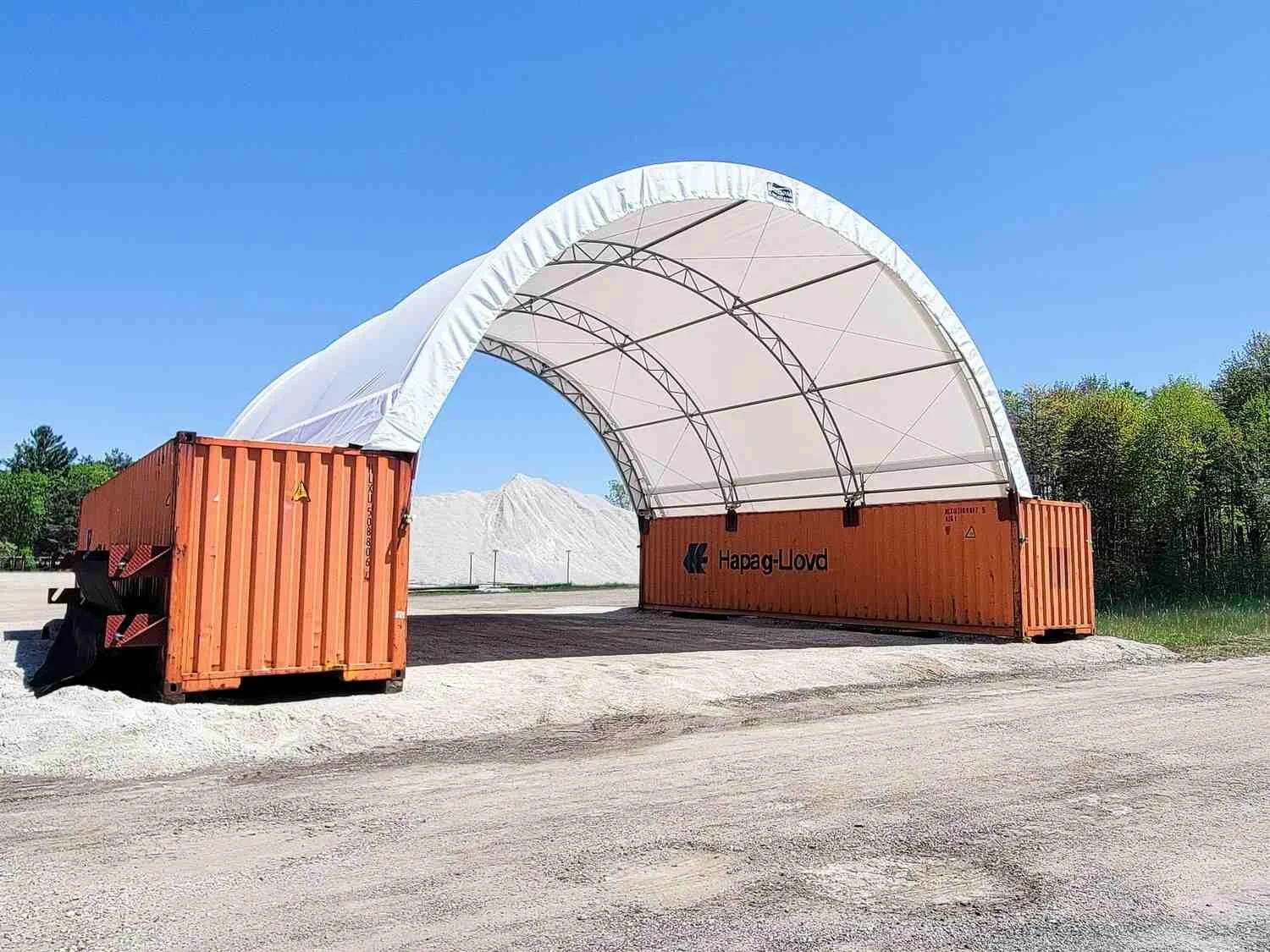 White fabric container canopy spanning two shipping containers for outdoor equipment storage