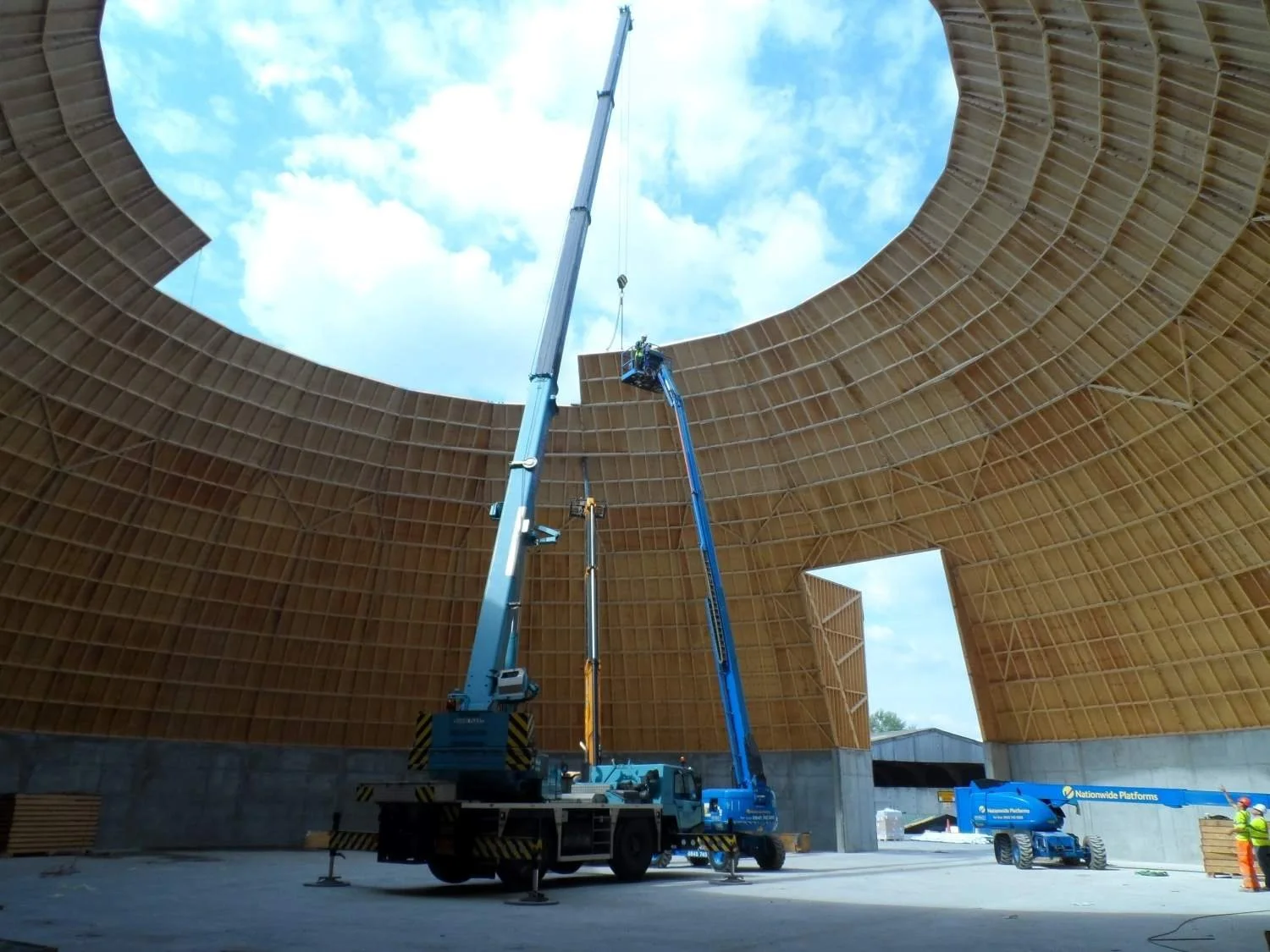 Interior view of a Eurodome timber barn under construction with cranes installing the engineered timber dome