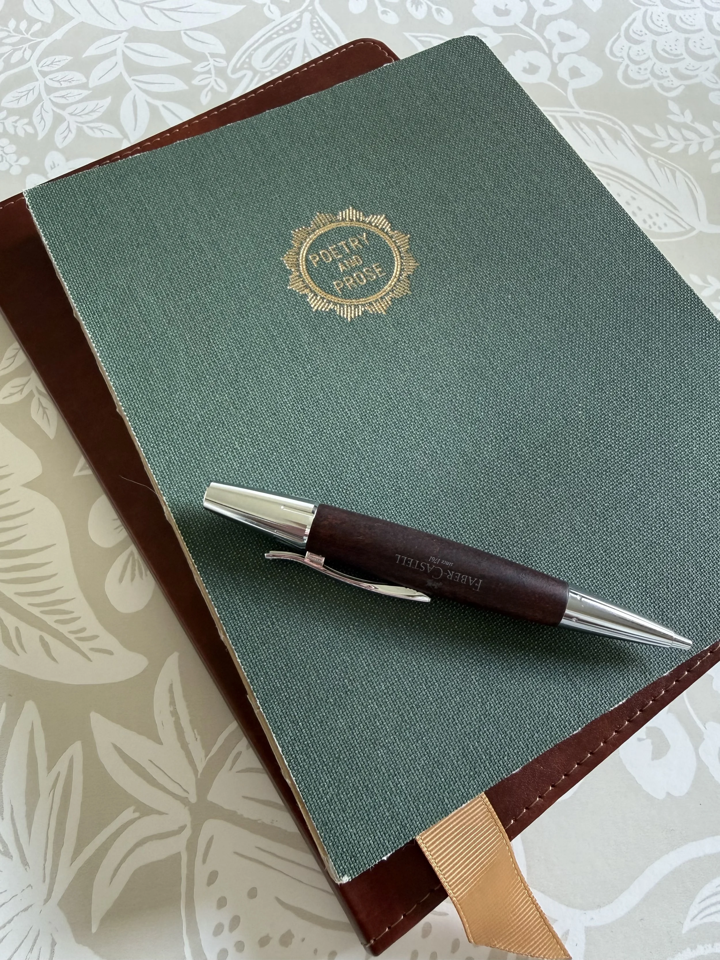 Green fabric Poetry and Prose notebook with a fountain pen resting across the cover.