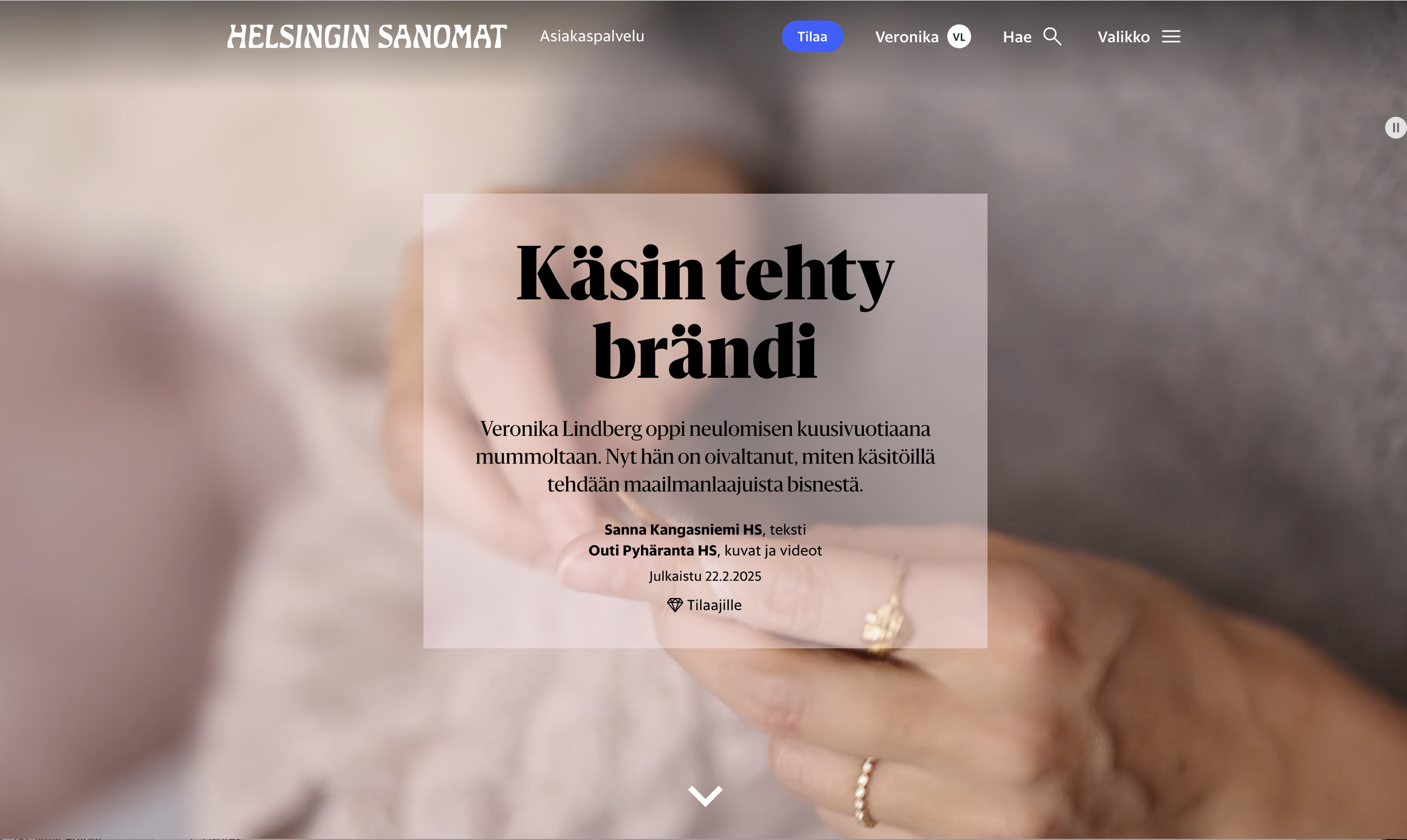 Close-up of a person's hand holding a small, round, golden object, with delicate jewelry on their fingers, blurred background.