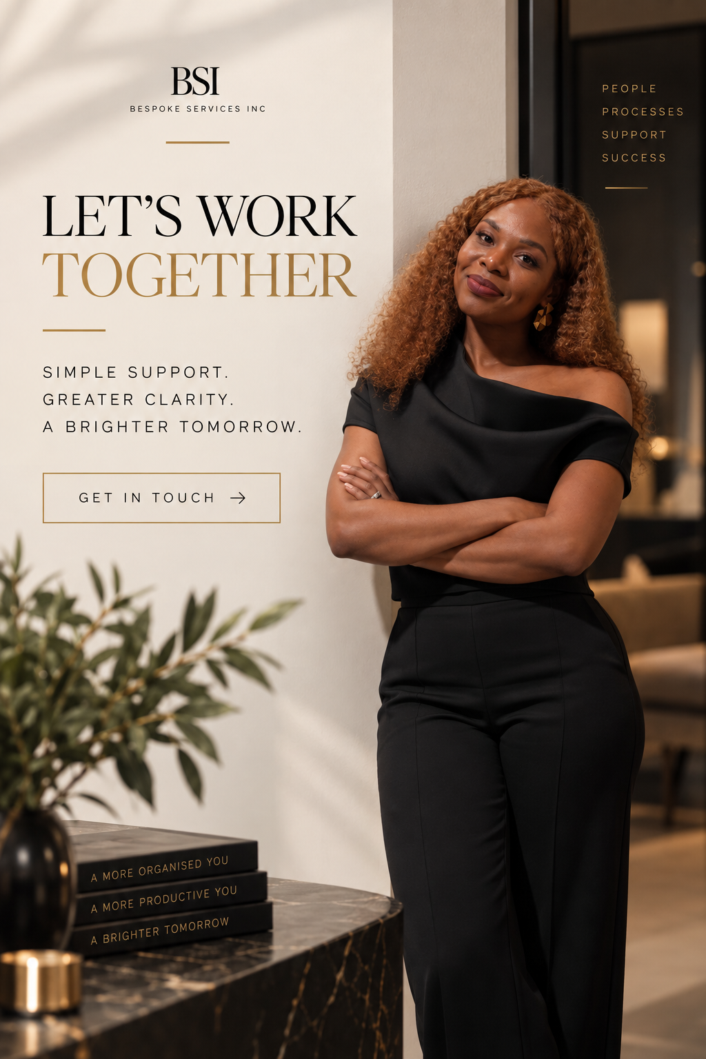 A woman with curly red hair in black attire standing next to a sign that reads 'Let's Work Together' with additional text about support and clarity, inside a professional office setting.