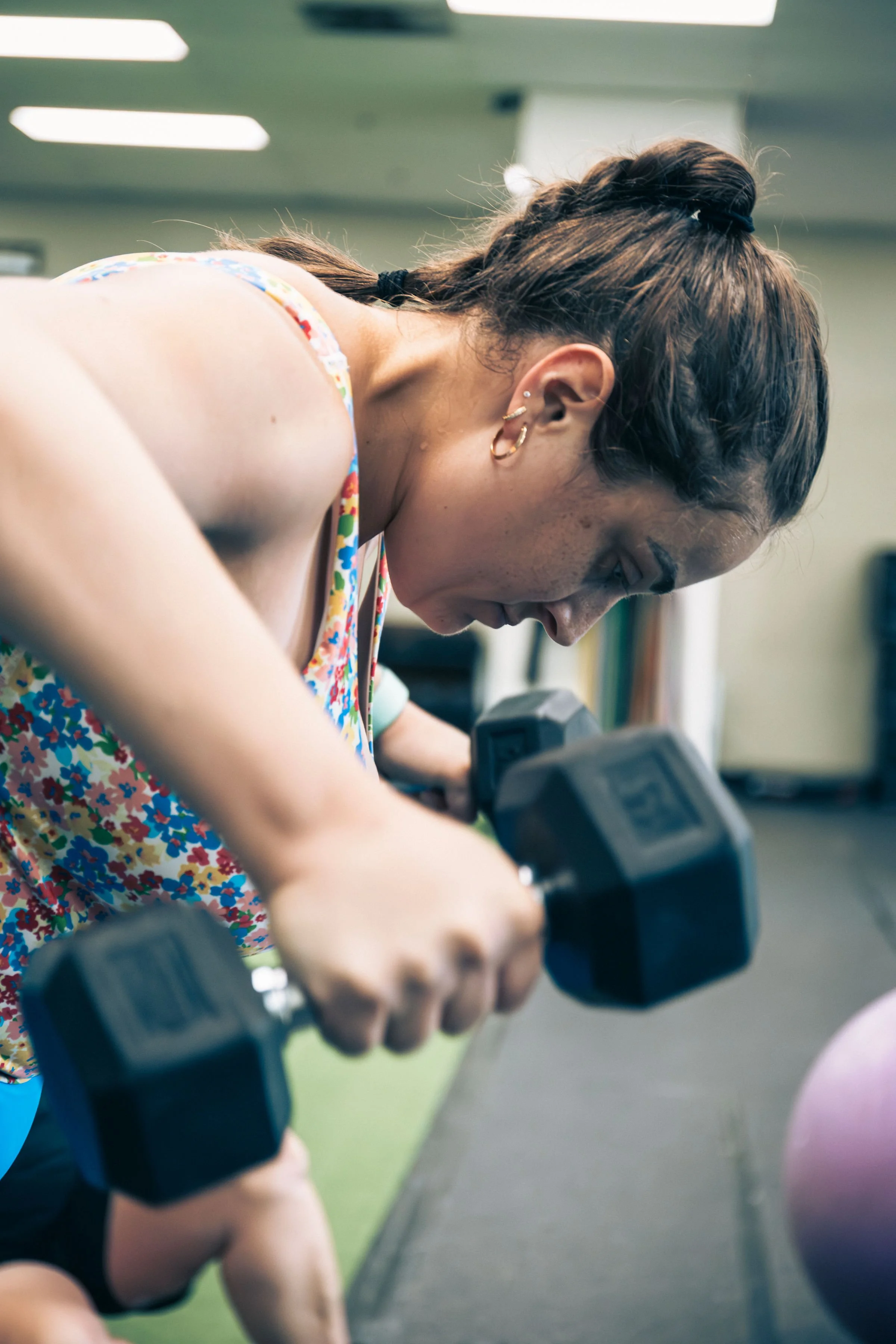 Close up image of a PFP client using dumbbells for shoulder and back exercises.