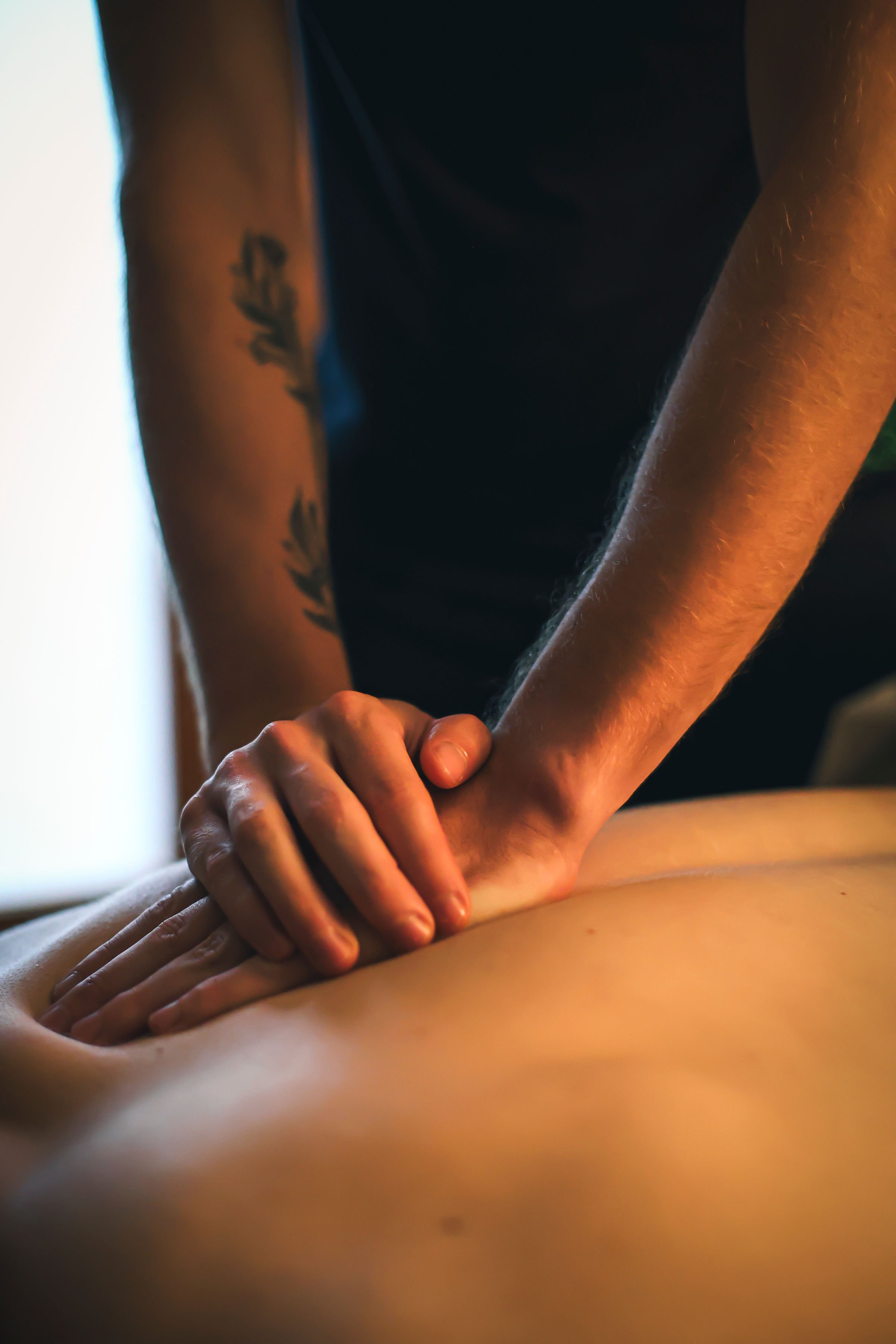 Close-up of one Raph's hands massaging another person's back in a dimly lit setting.