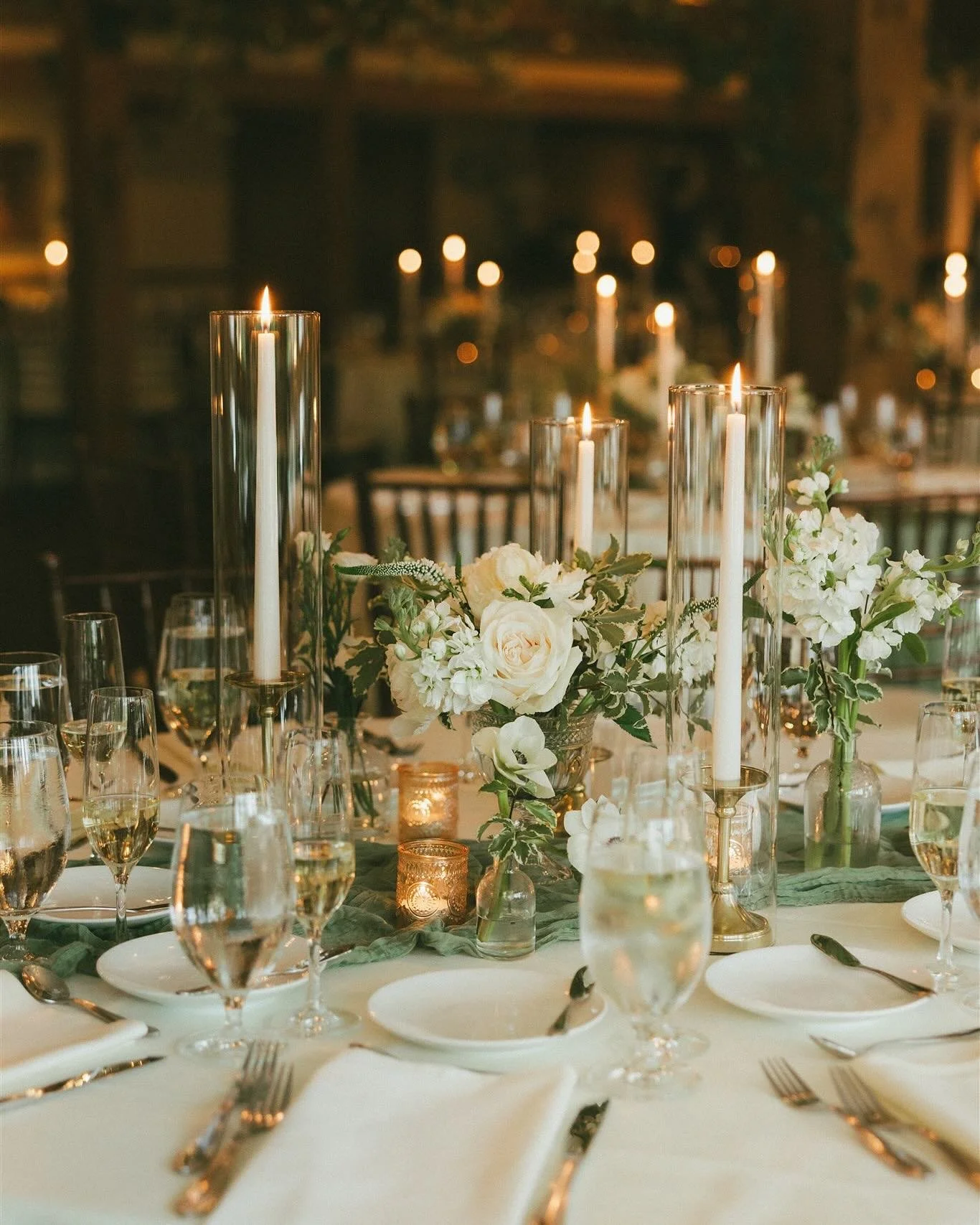 Lexi and Harry&rsquo;s wedding gave Victorian greenhouse vibes with guest tables topped with a small arrangement in a vintage cut glass vessel, medicine bottle budvases, and elegant taper candles. We also went wild with hanging greenery from the beau