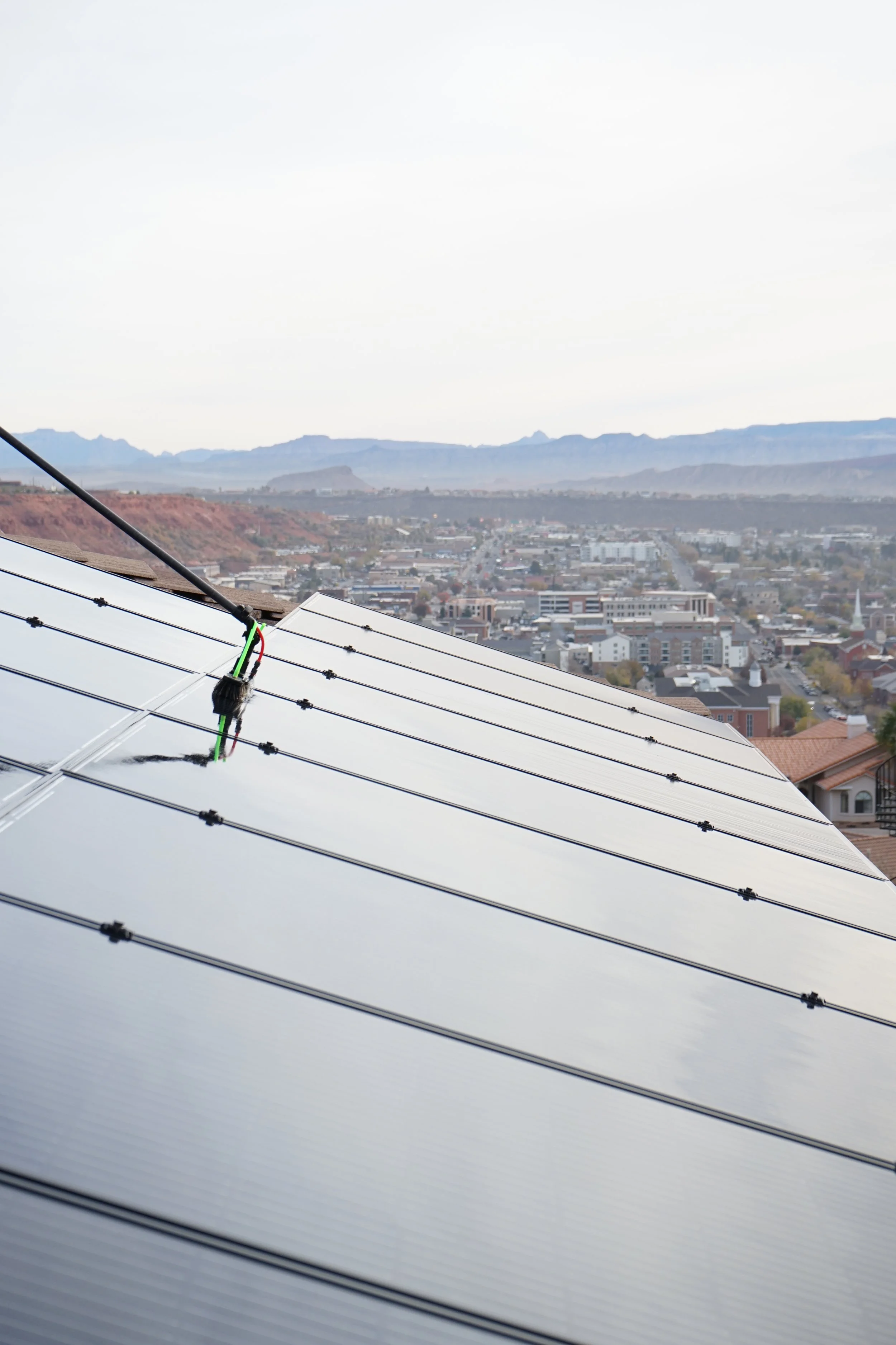 Picture of our tech professionally cleaning solar panels in St. George Utah. Using a brush to loosen all of the dirty on the solar panels.
