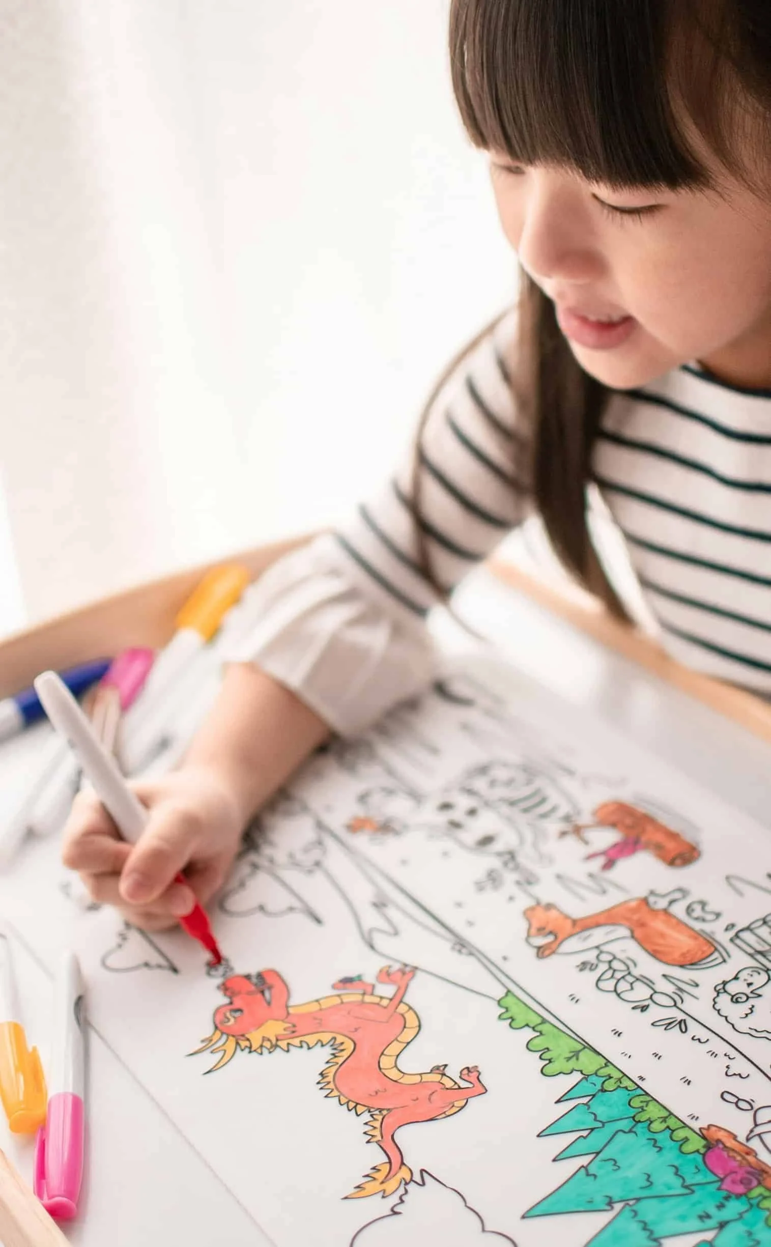 little girl sitting at table and drawing