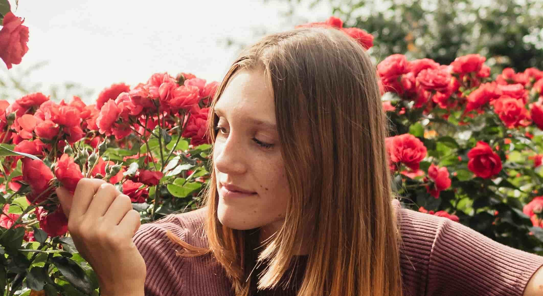 teen girl holding red flowers while looking at them
