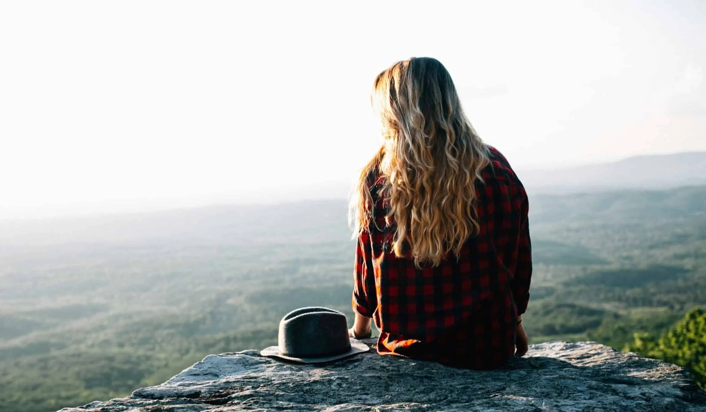 girl sitting on cliff and thinking while staring into distance