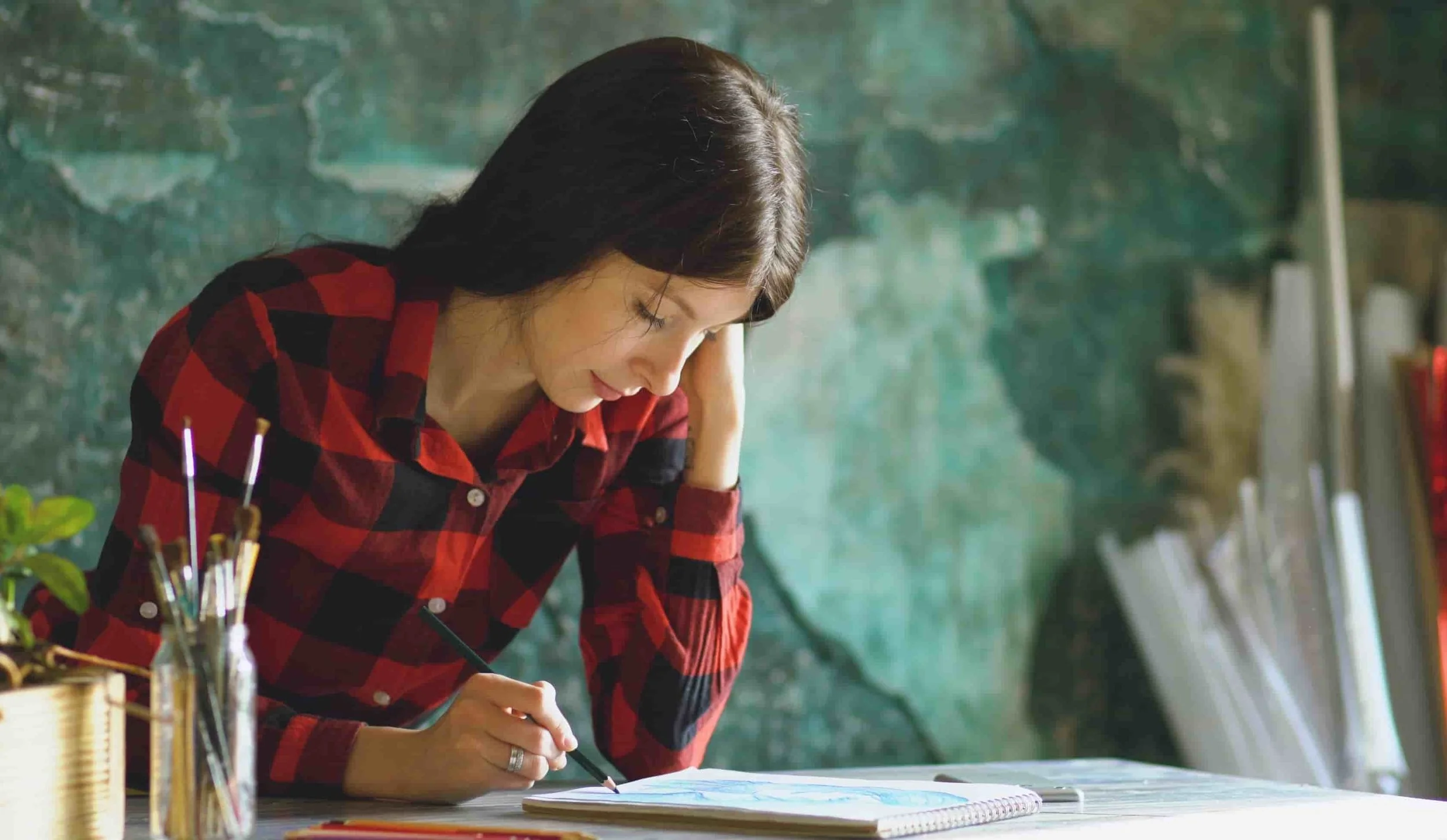 teenage girl sitting at desk and writing in notebook