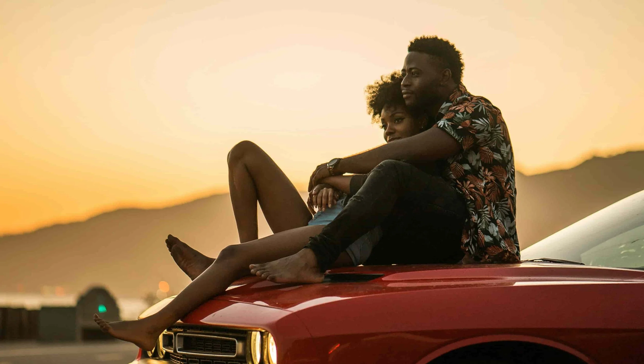 couple back hugging while sitting on car