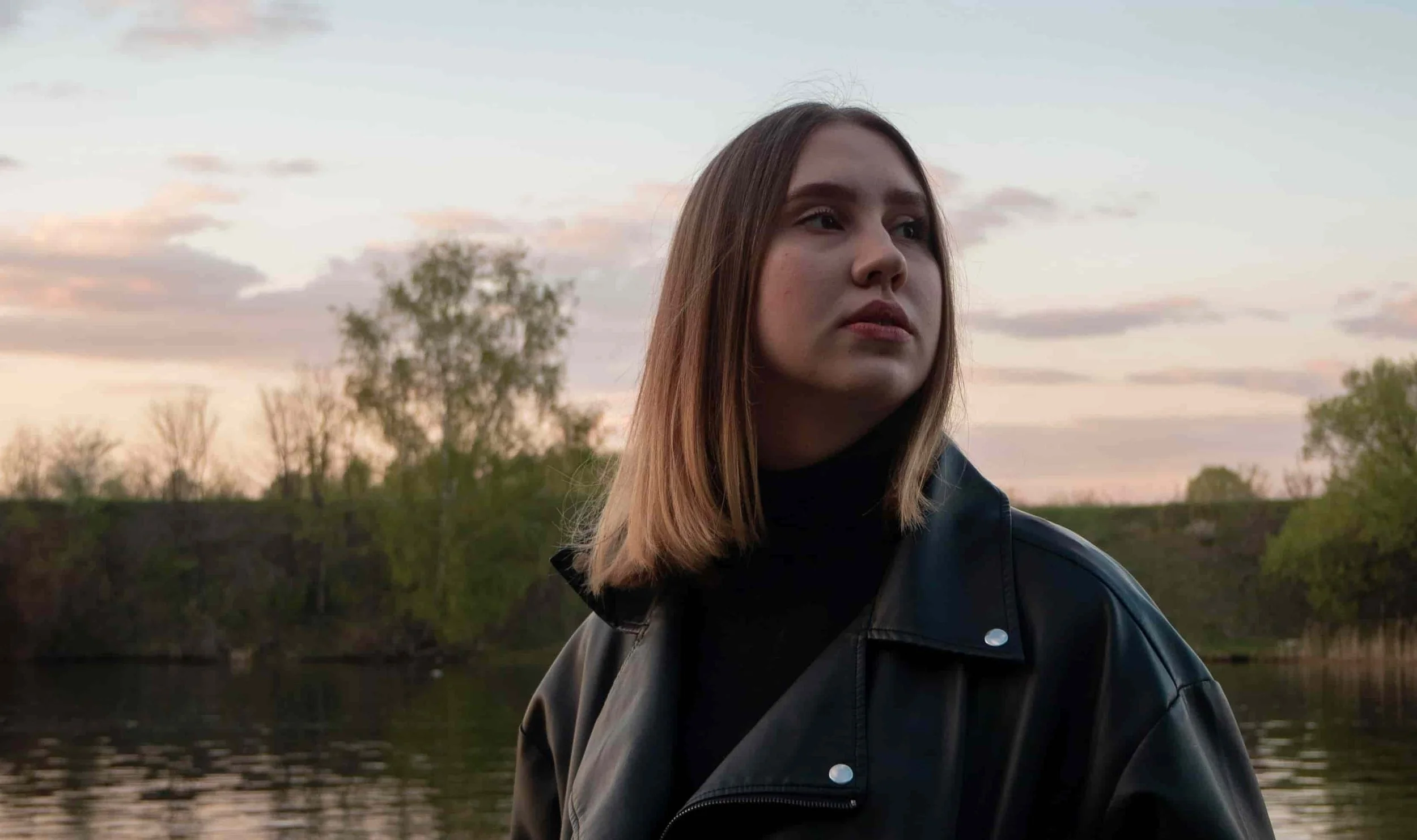 woman looking into distance while standing by lake