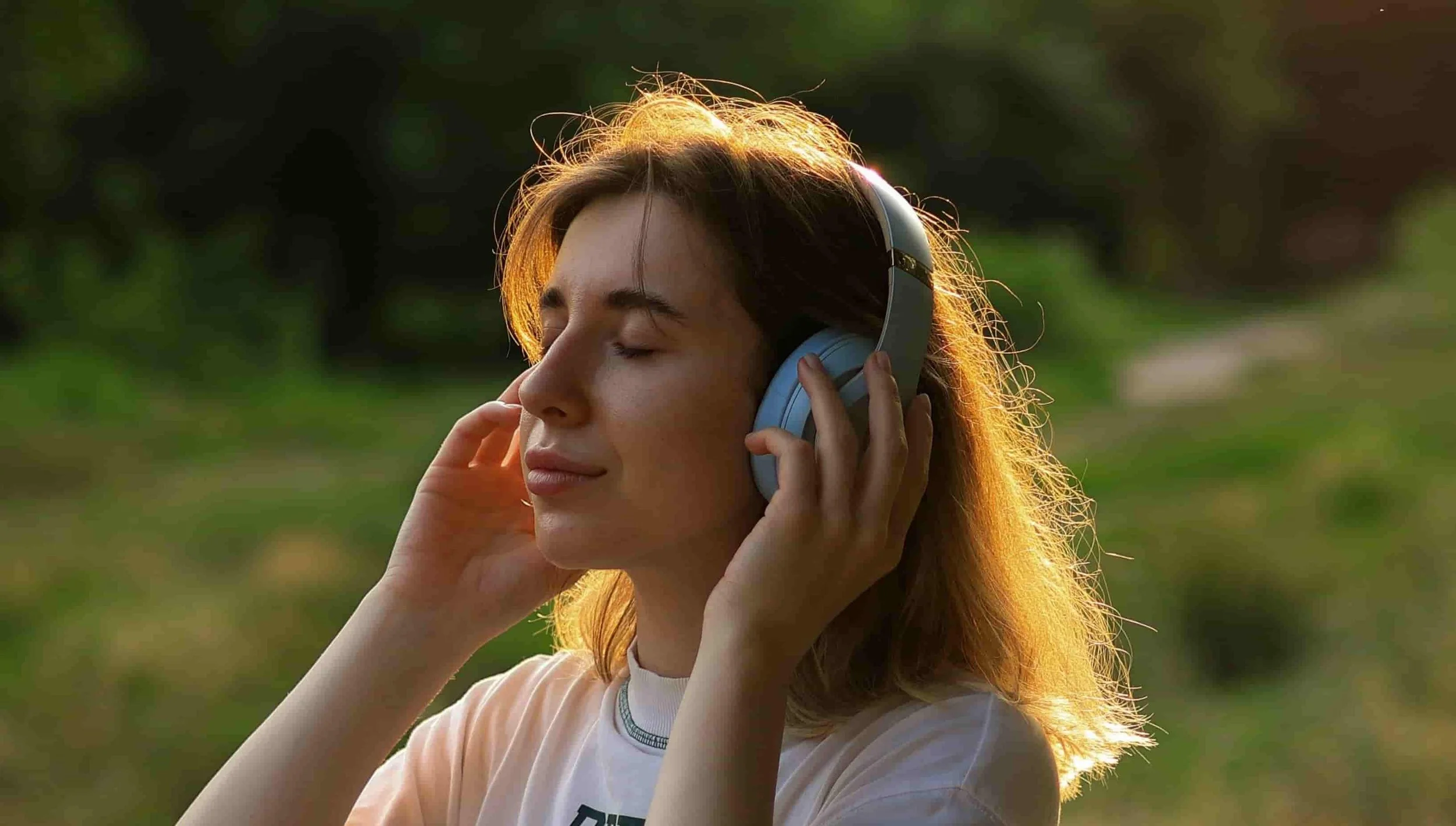 woman listening to music with eyes closed in grass field