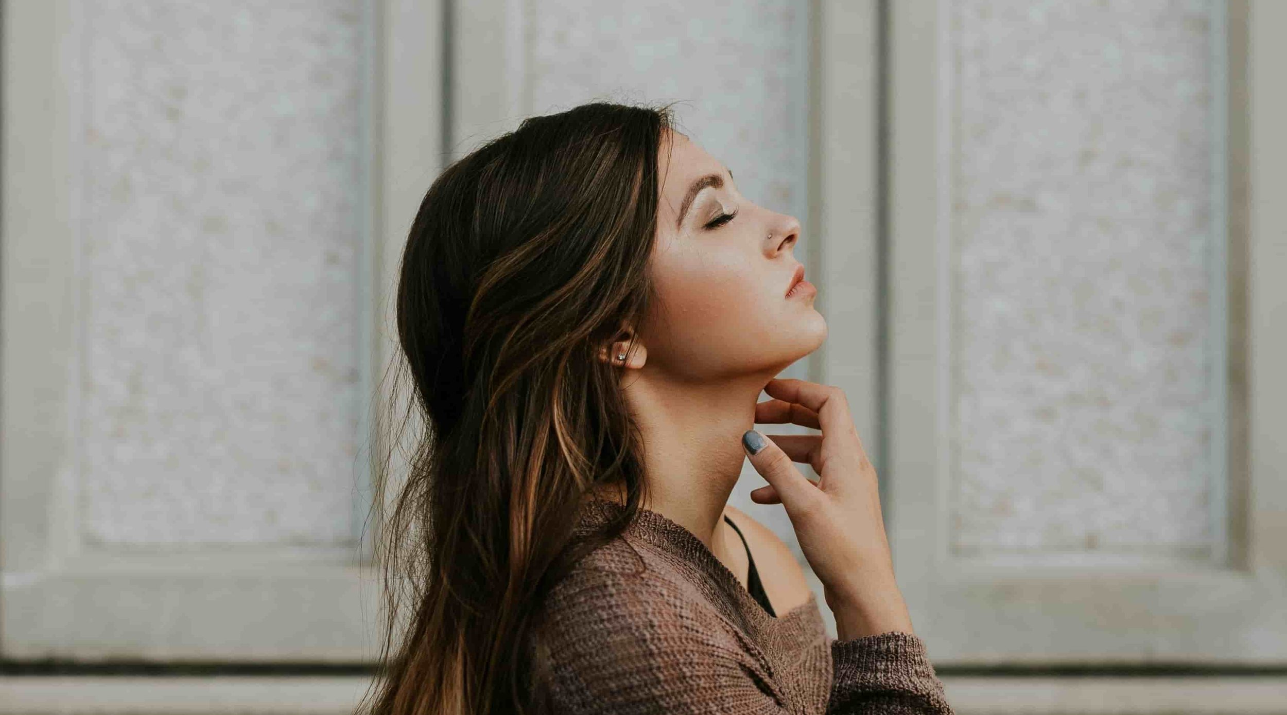 woman closing her eyes and looking up at the sky