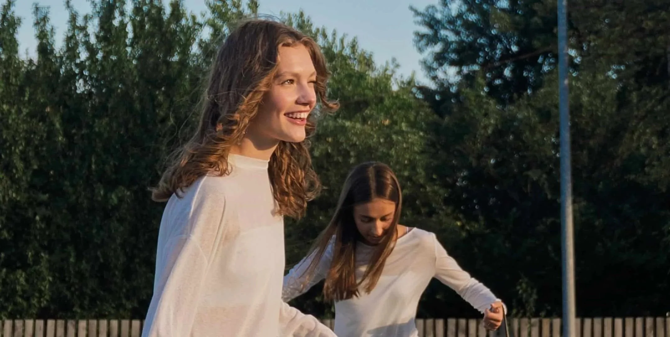 two girls skateboarding in parking lot