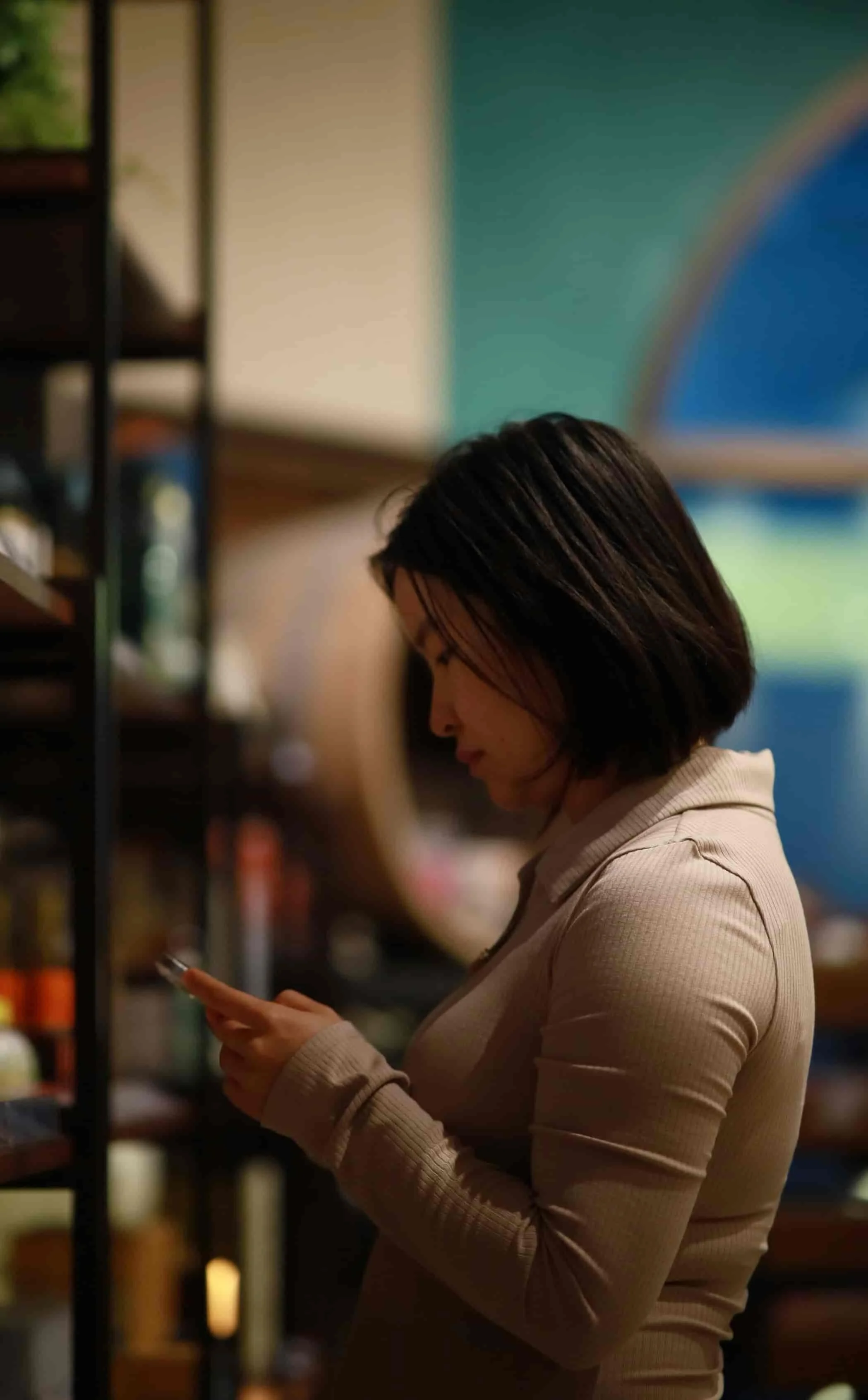 woman standing in front of shelves and looking at phone