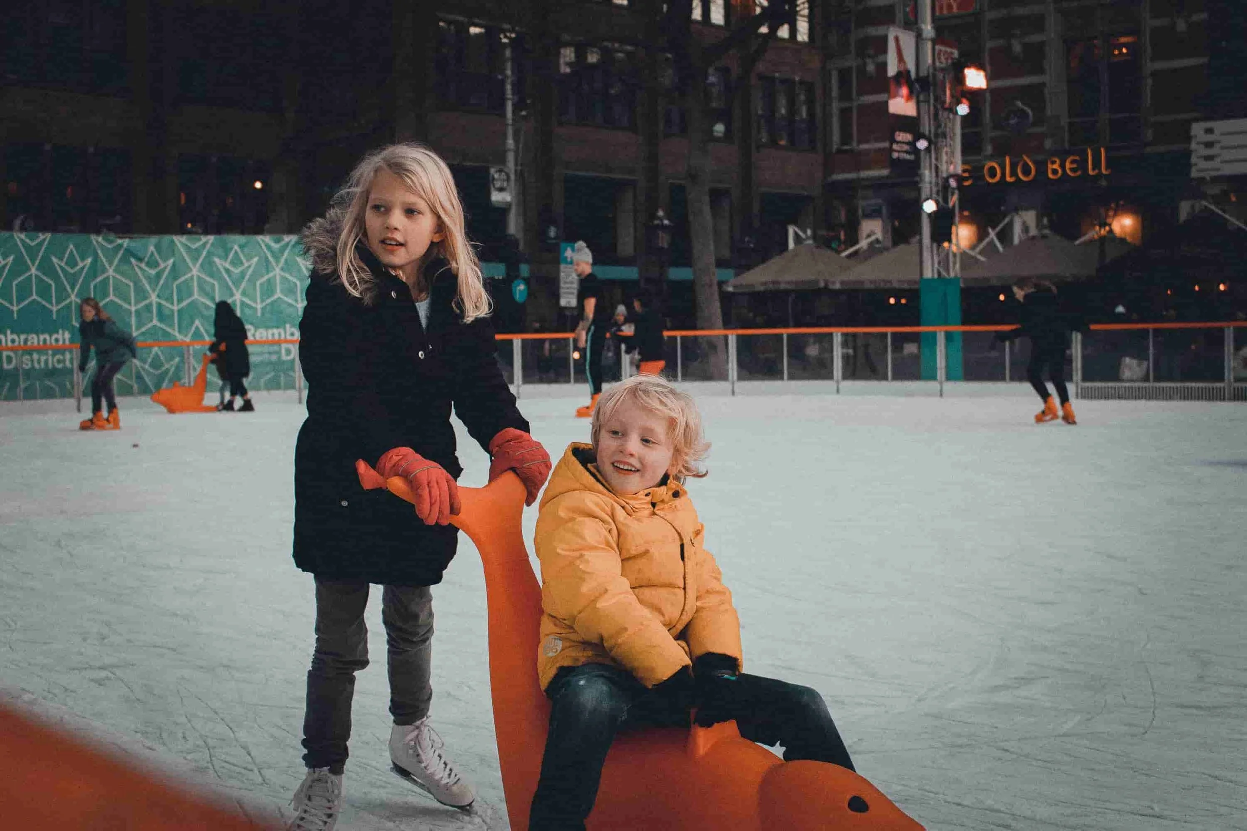 sister pushing brother on skating rink