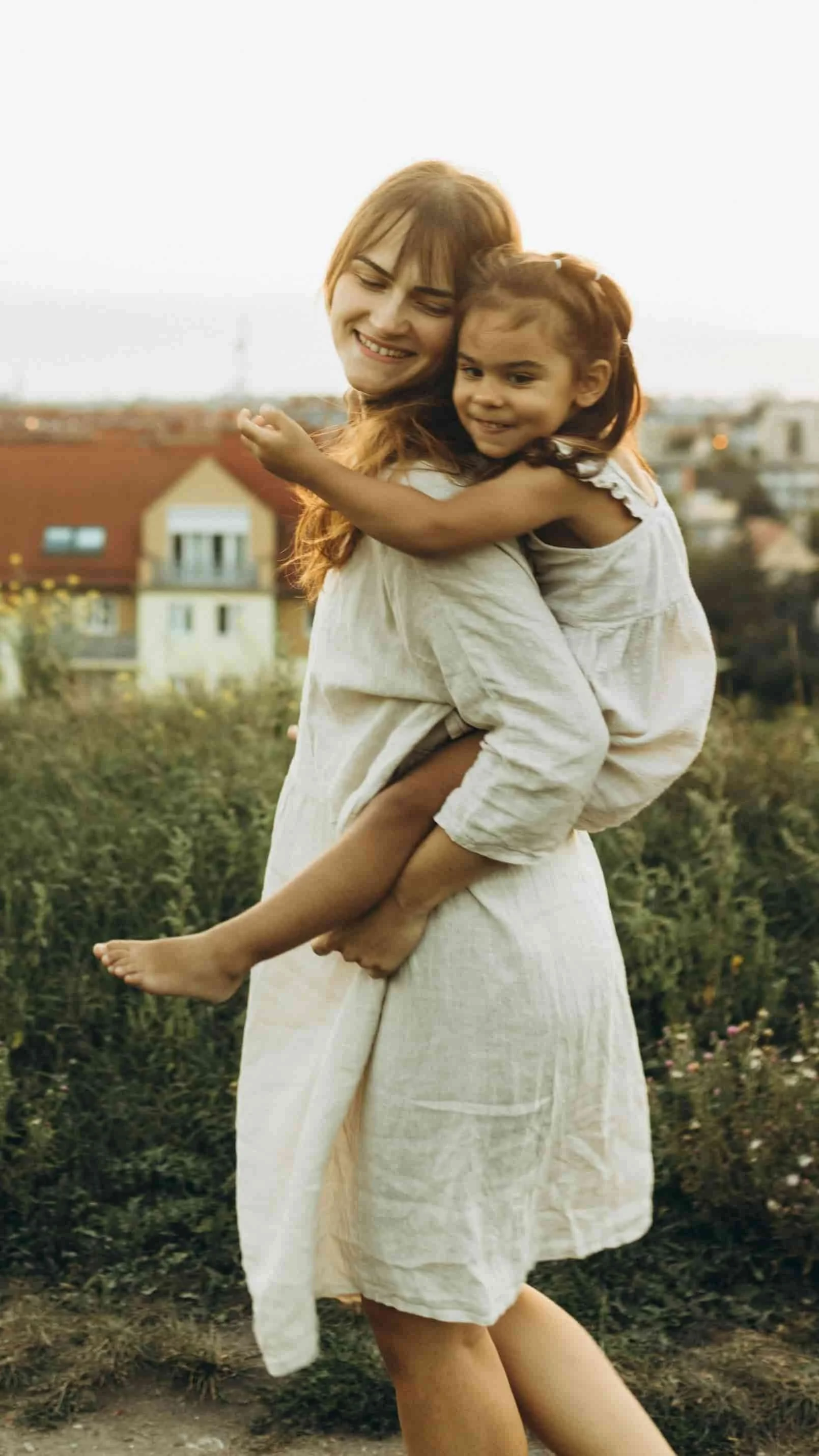mom giving daughter piggy back ride while standing in field