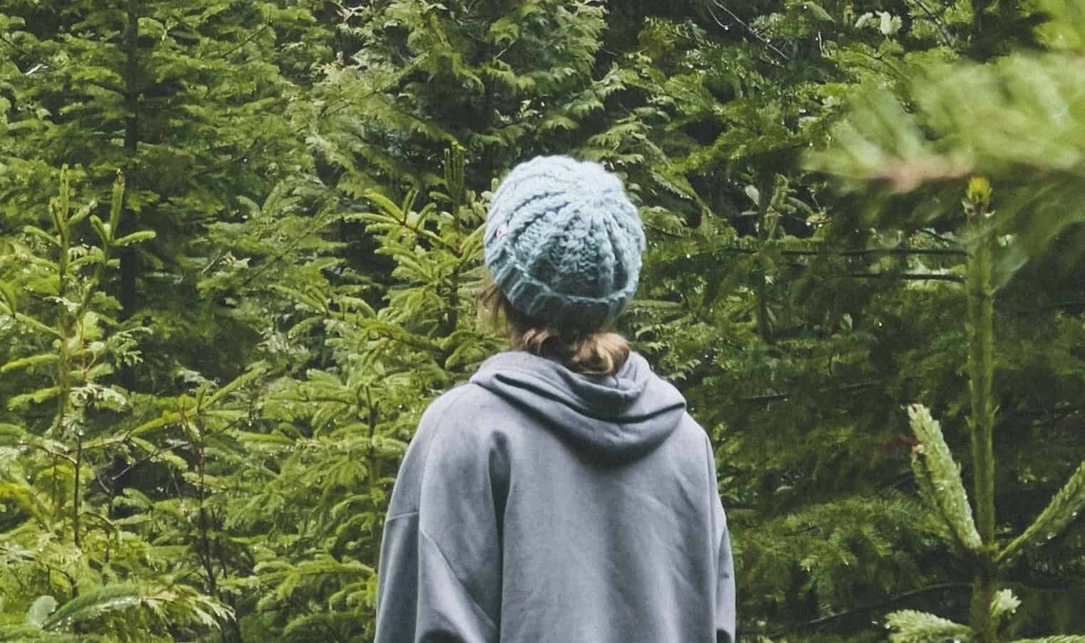 girl standing in forest looking at trees